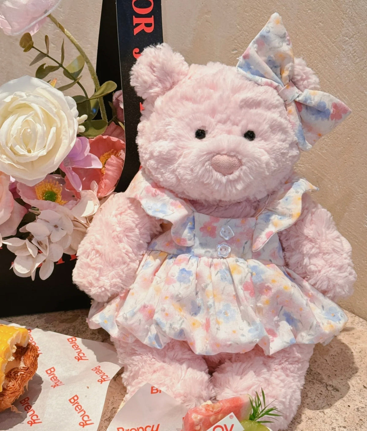 Front view of the pastel floral plush dress showing flutter shoulders, two buttons, gathered skirt and matching bow