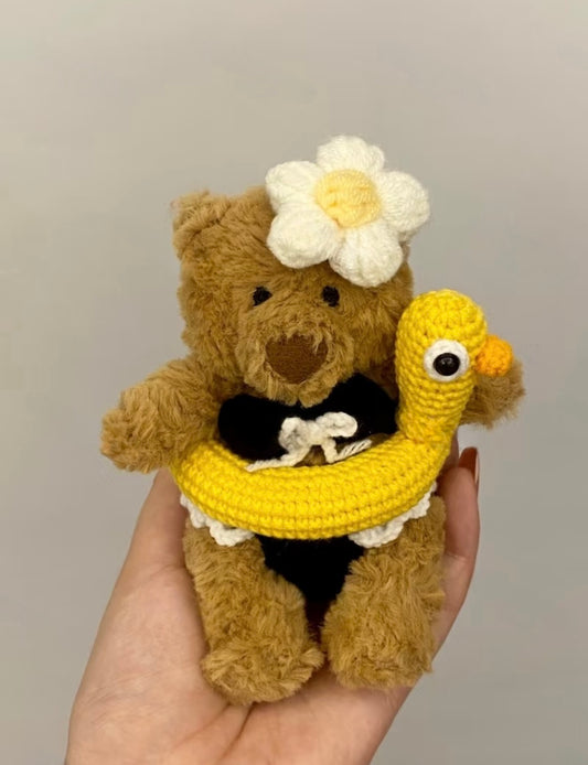 Bartholomew Bear holding yellow crochet duck ring float wearing black bikini set