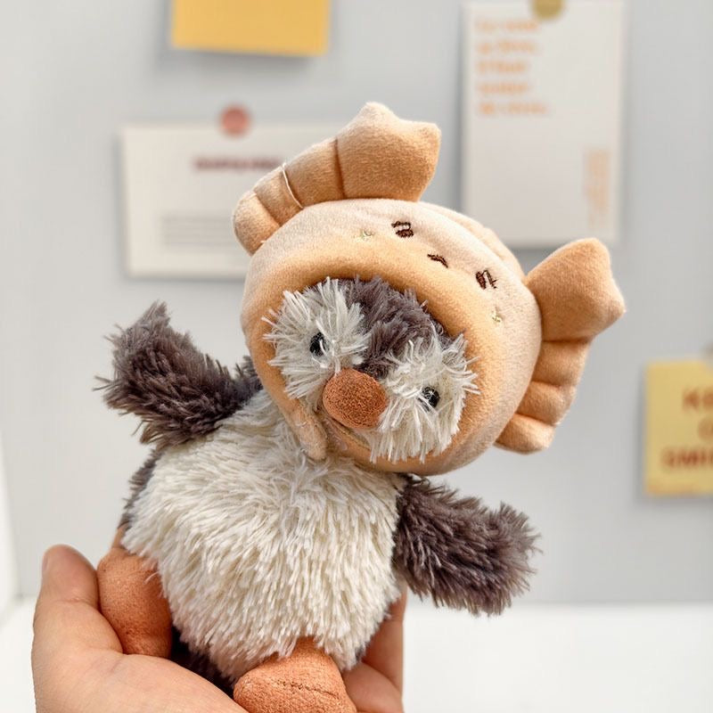 Jellycat Peanut Penguin wearing beige cookie hoodie hat with chocolate chip embroidery