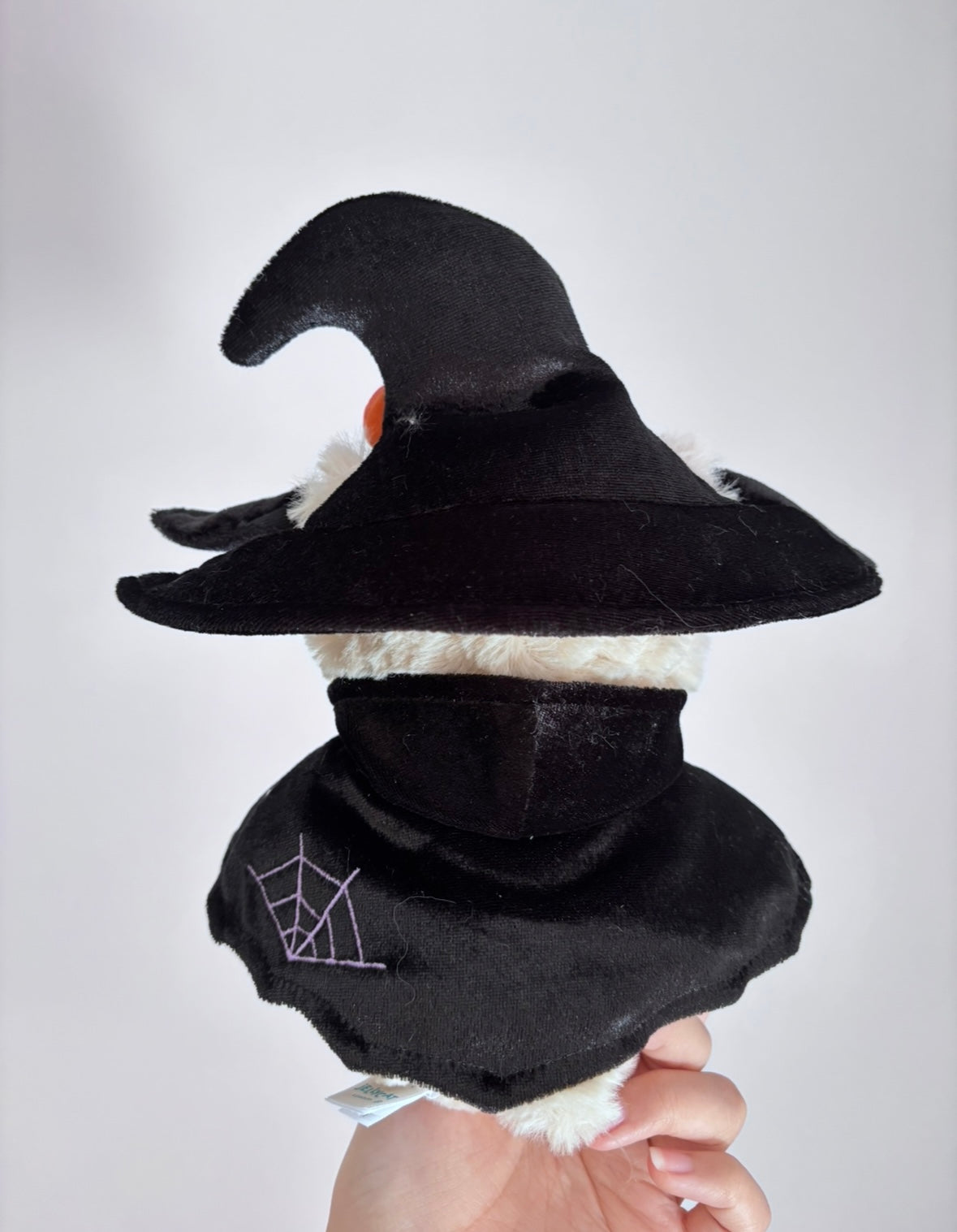 Plush bear wearing black velvet witch hat and ghost cape with purple and white ghost appliqués