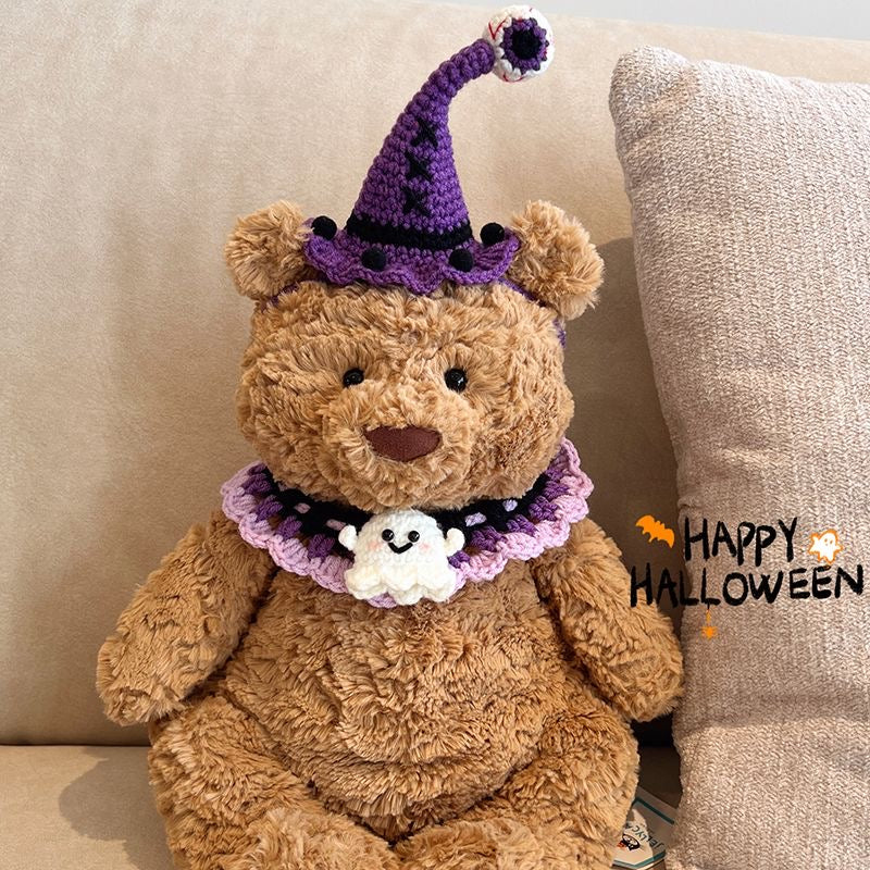 Plush bear wearing a handcrafted purple crochet witch hat with pompom and a purple ghost collar