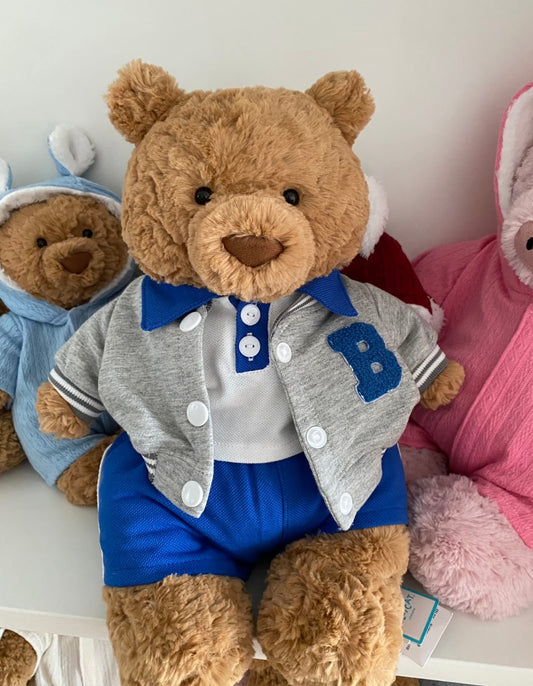 Teddy bear wearing grey varsity jacket with blue B patch and royal blue shorts