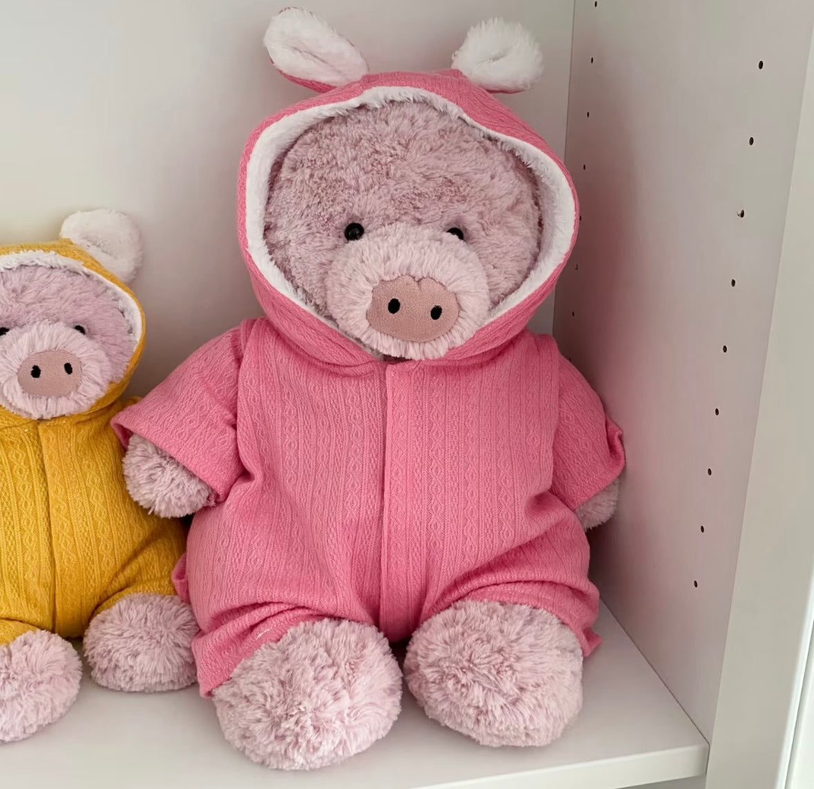Bears and a plush pig in red, cream, blue and pink hooded rompers