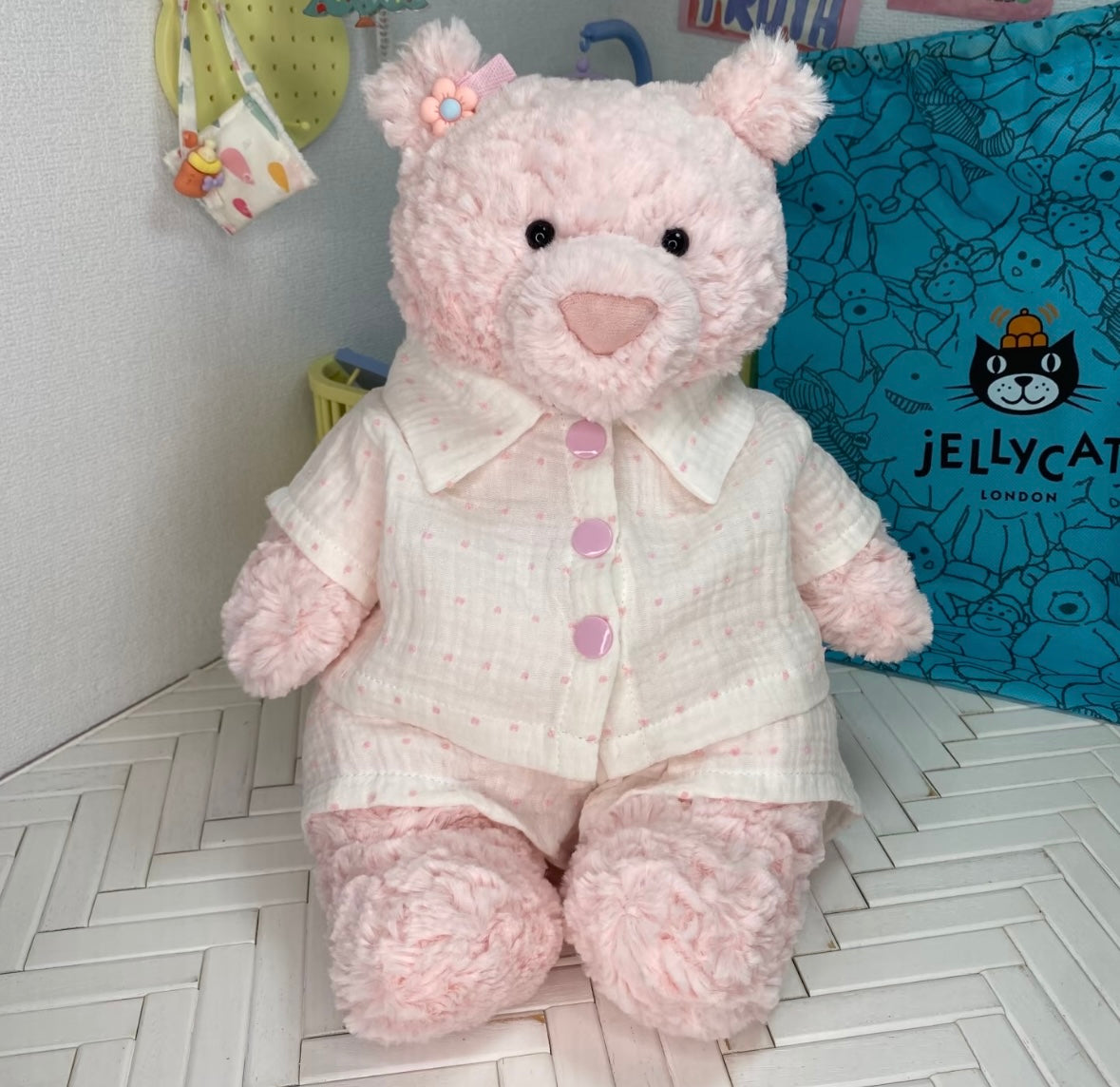 Pink teddy bear wearing cream muslin pyjamas with tiny pink dots and pink buttons