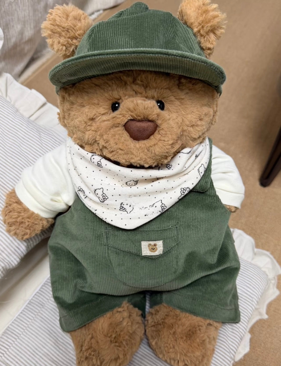 Bartholomew Bear wearing a green corduroy outfit with matching cap and printed bandana