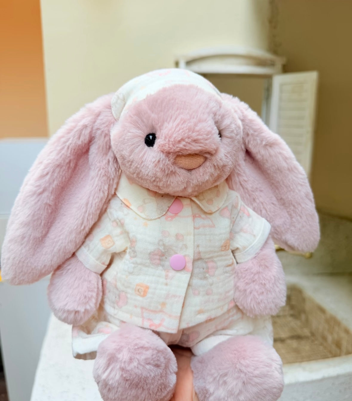 Pink bunny in pastel outfit seated beside another bunny wearing a different printed outfit