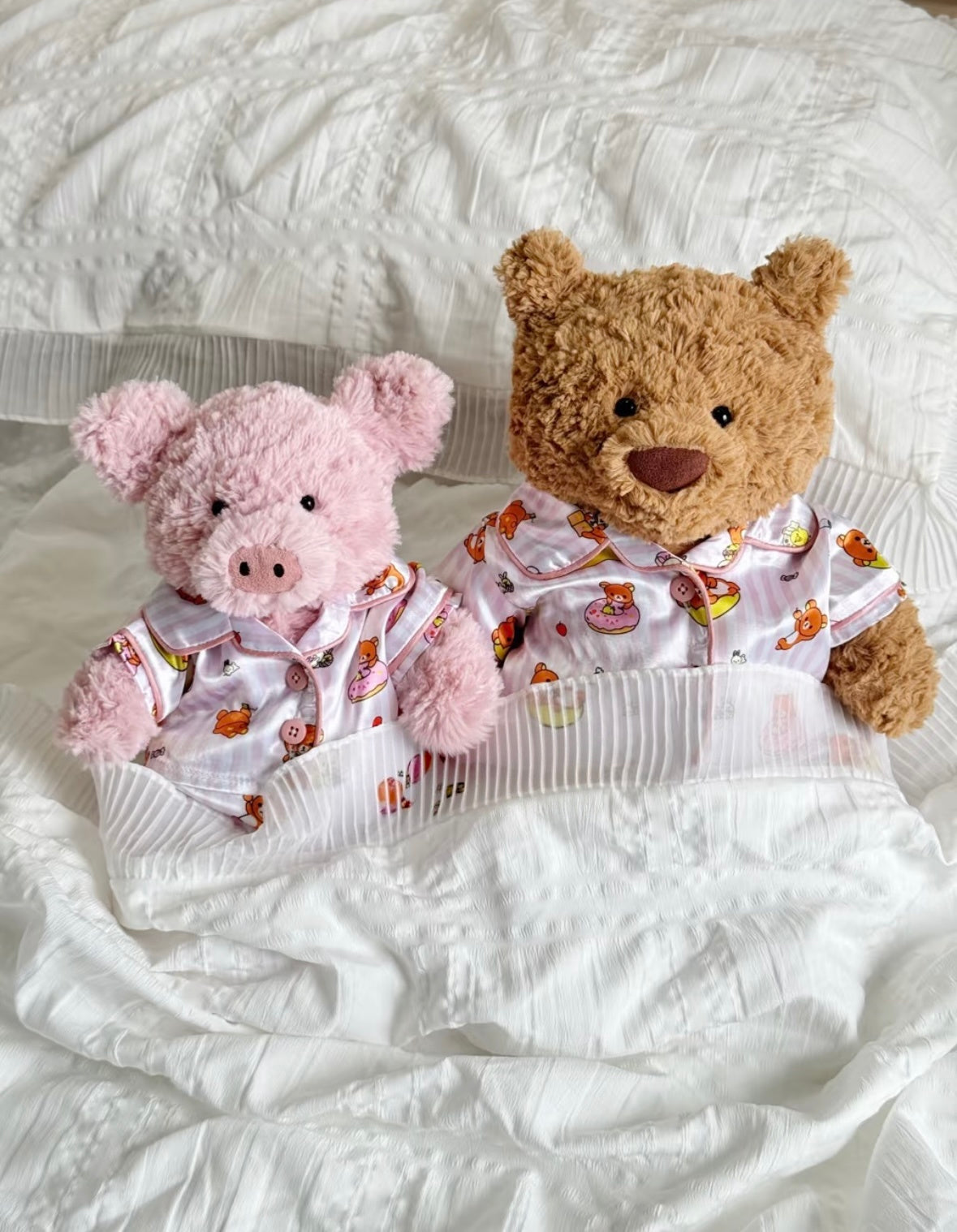 Bear and pink pig plush toys tucked into bedding wearing collared Rilakkuma-print pyjama tops.