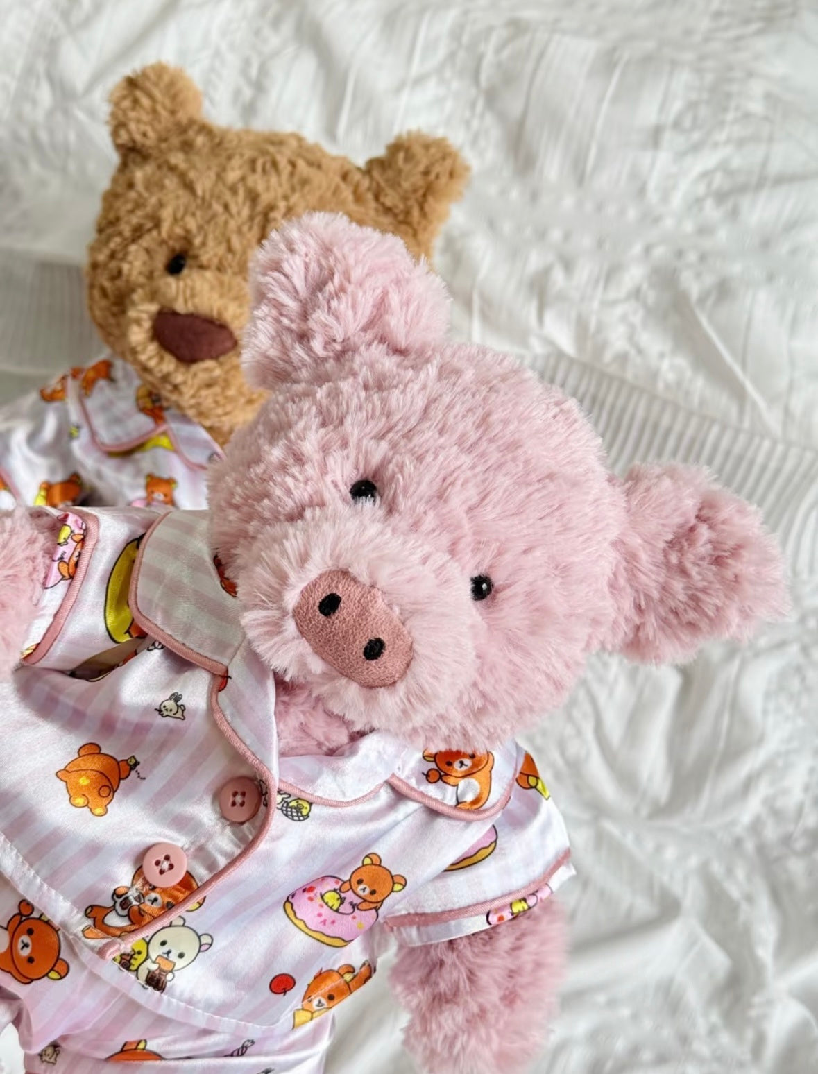 Close-up of the pink Rilakkuma-print pyjama top with pink piping and button details on a pig plush.