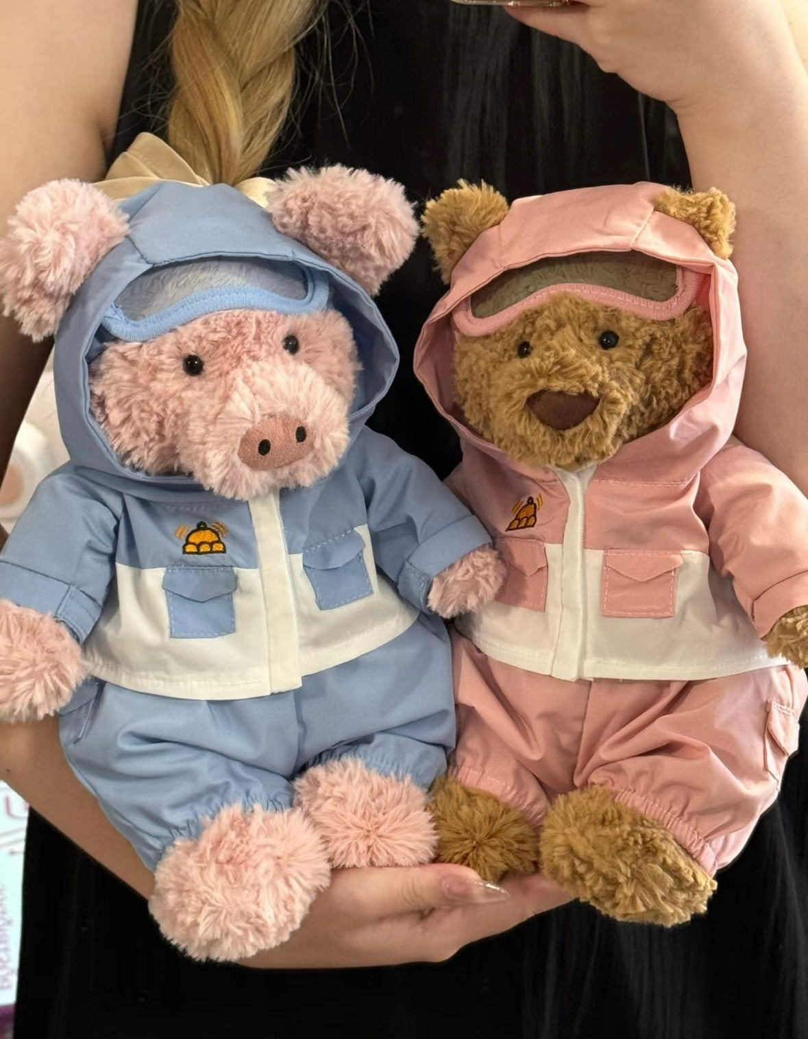 Front view of the pink ski outfit with a hooded jacket, cream panel and matching trousers on a pig plush.
