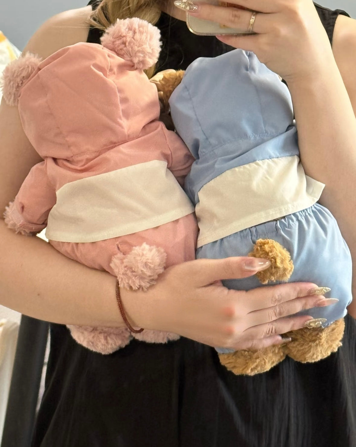 Back view of pink and blue hooded ski outfits with cream jacket panels on plush toys.