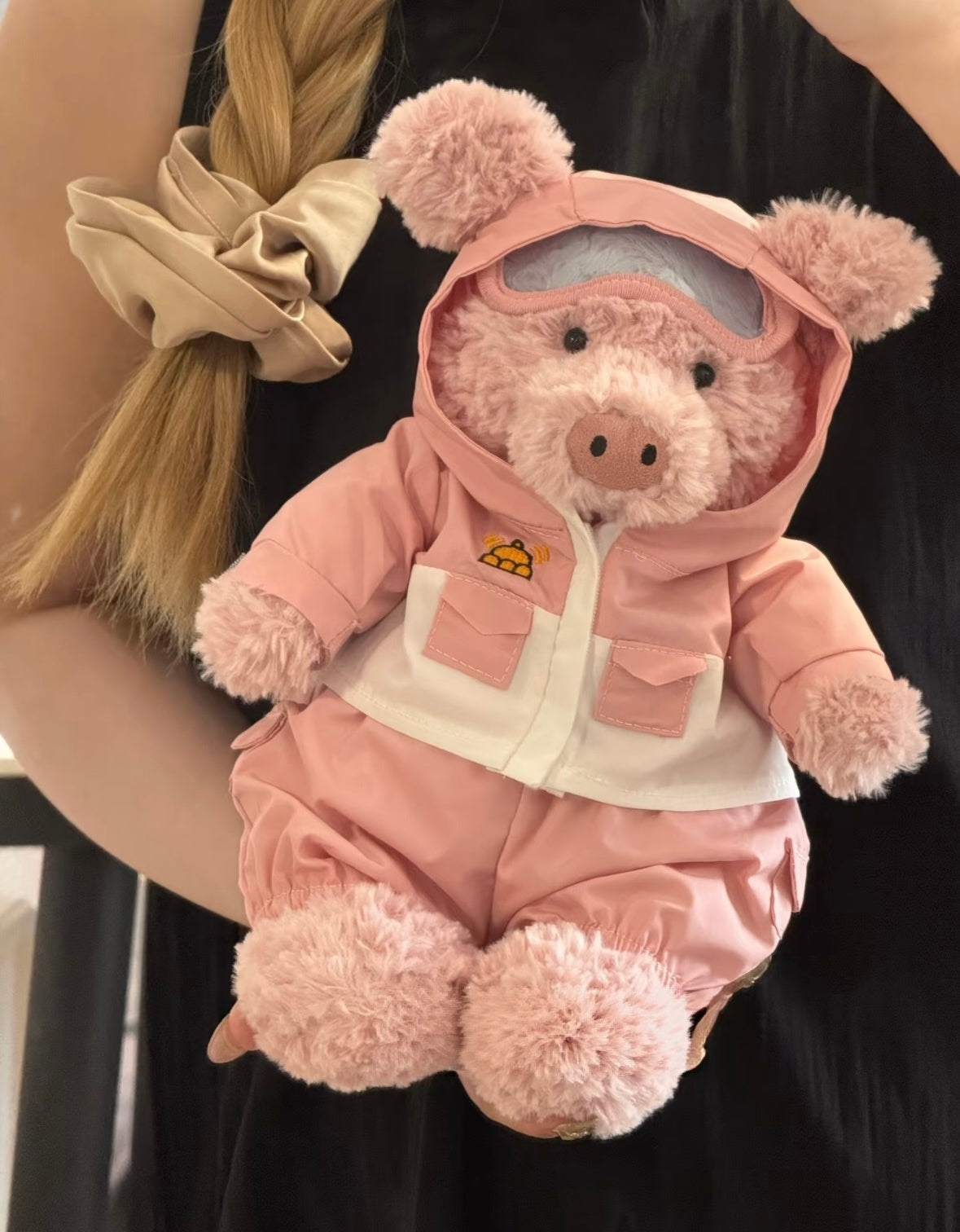 Front view of blue and pink ski outfits with pocket details and matching trousers on pig and bear plush toys.