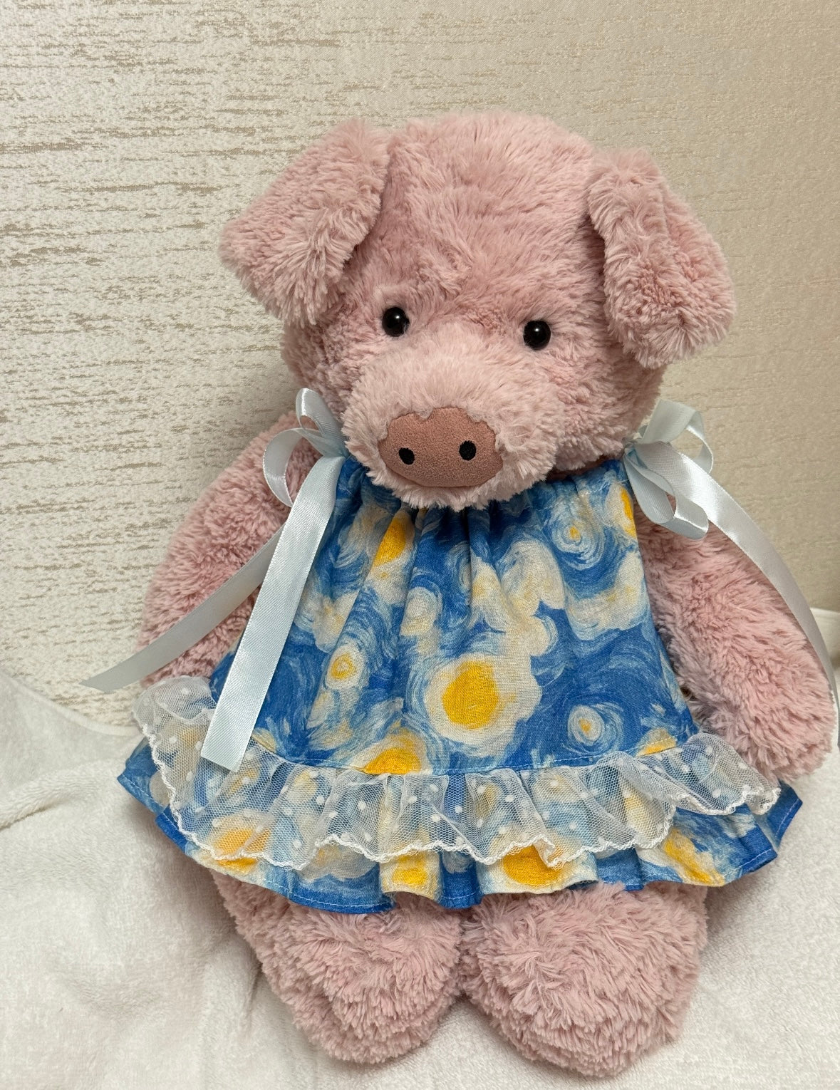 Pink plush pig modelling the blue and yellow dress with pale ribbon shoulder ties and dotted lace ruffle