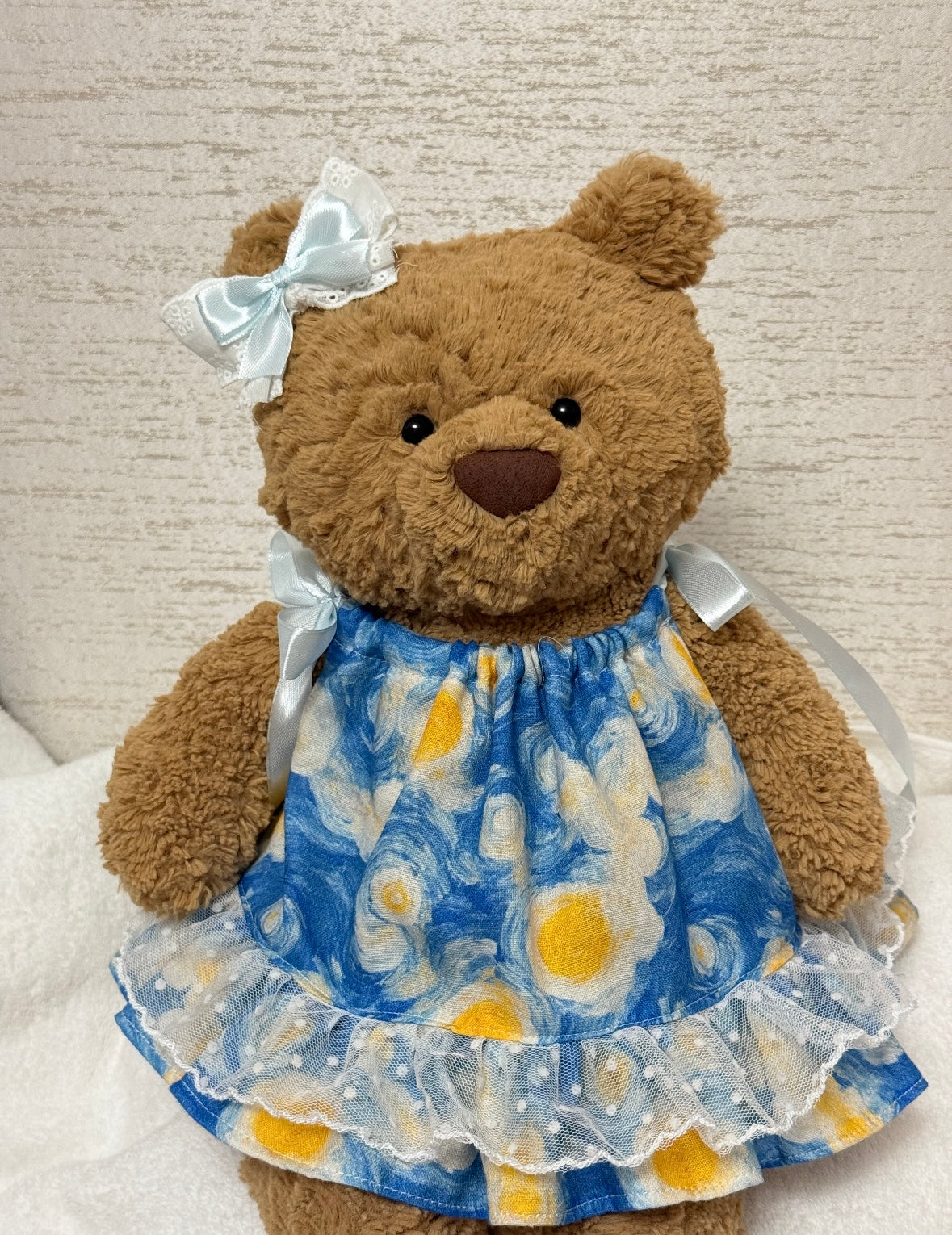 Bartholomew Bear wearing the blue and yellow dress set with matching ribbon-and-lace bow