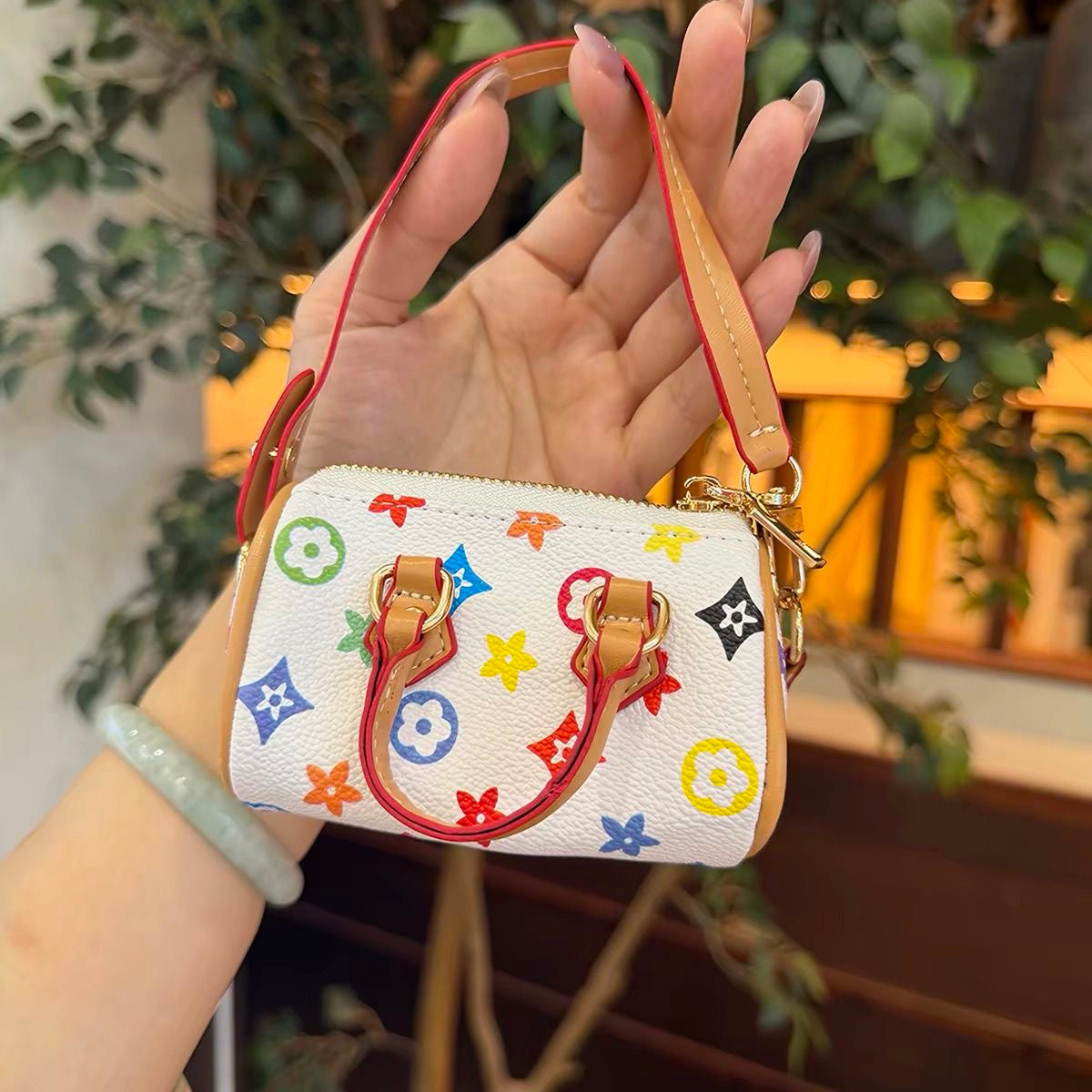 Mini black handbag with multicoloured floral and geometric motifs, tan handles and a long strap