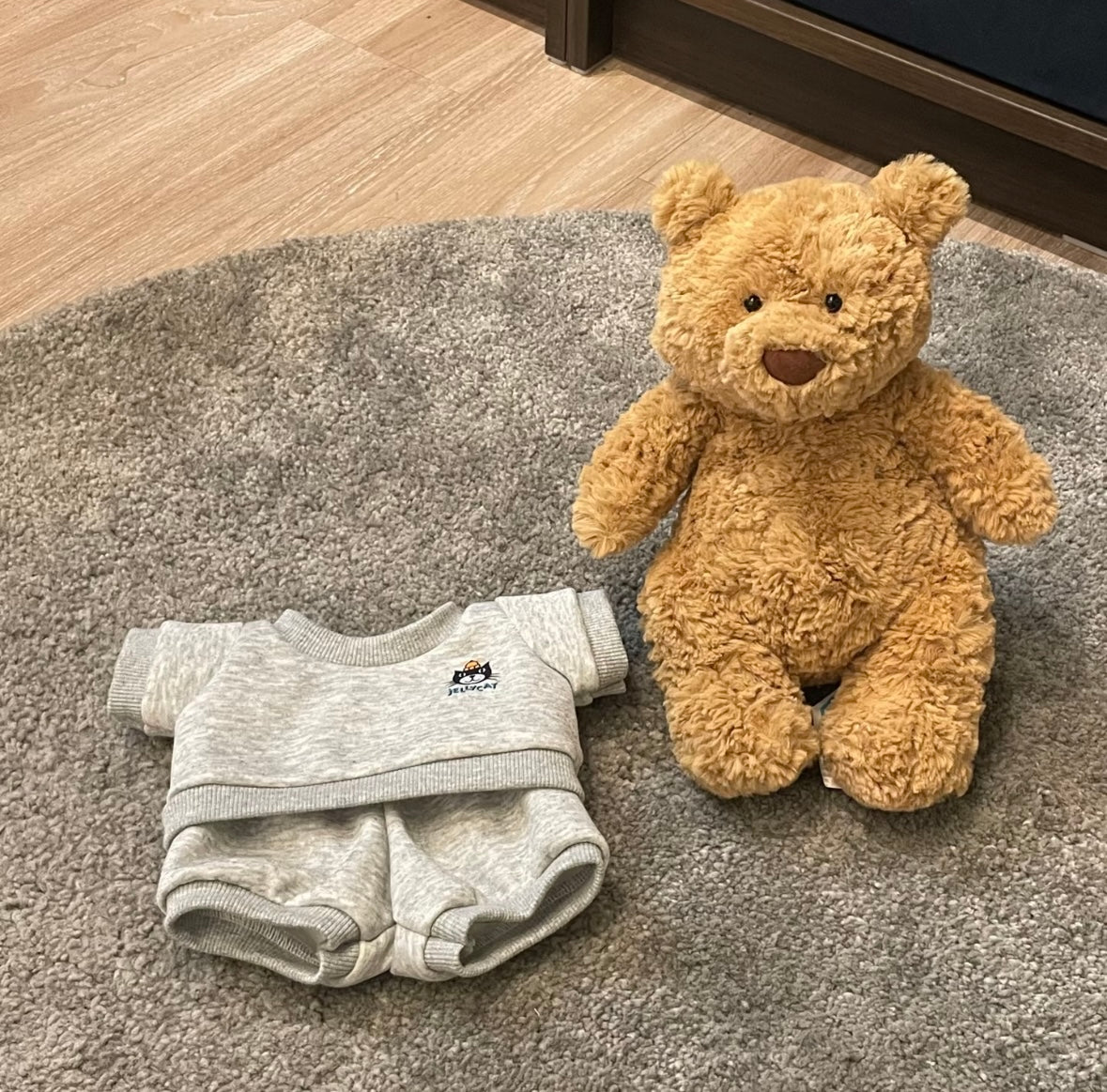 Small bear next to grey Jellycat sweatsuit set flat lay