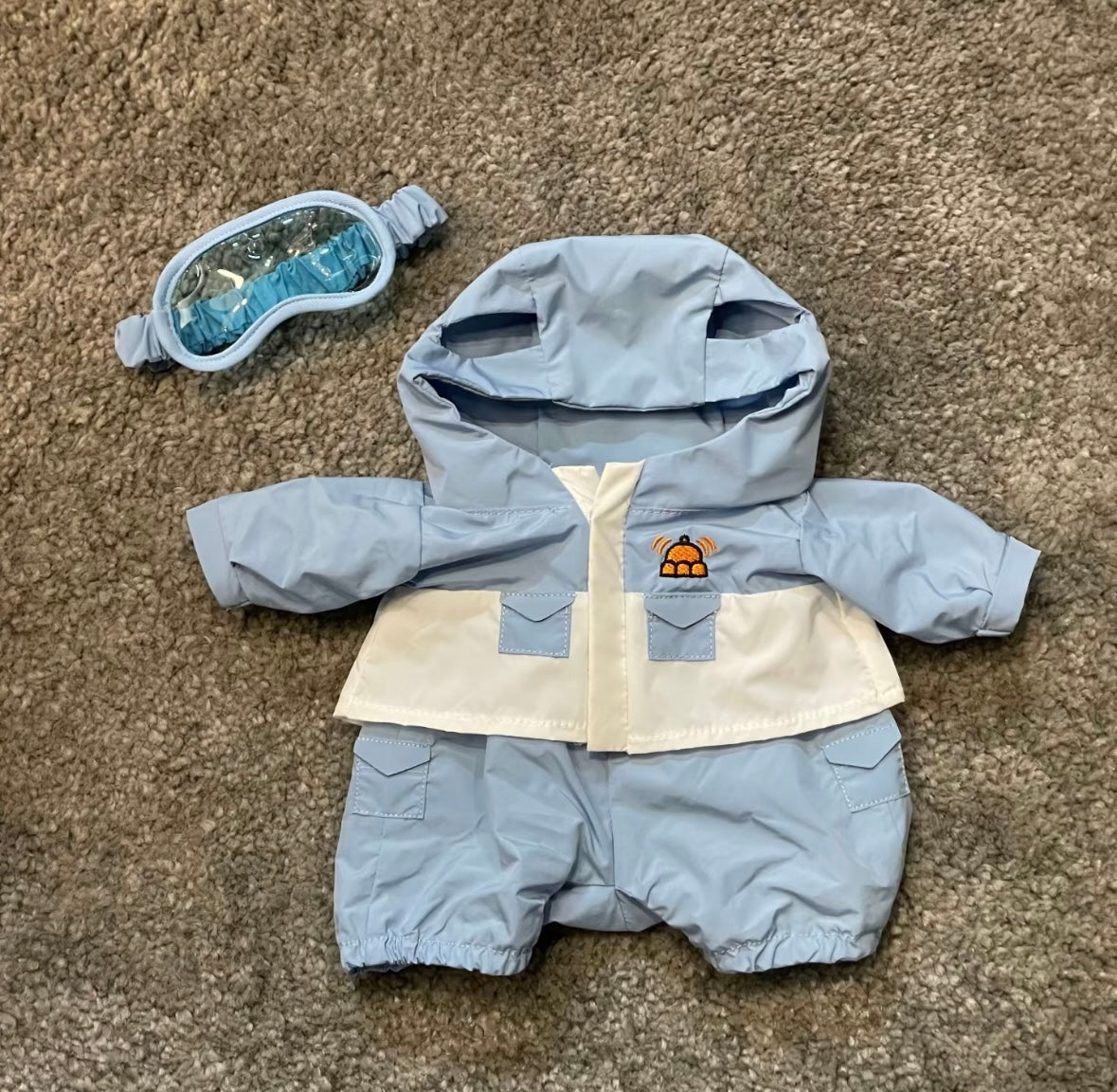 Baby blue snow suit and ski goggles flat lay