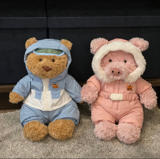 Bear in blue snow suit next to pink pig in pink snow suit