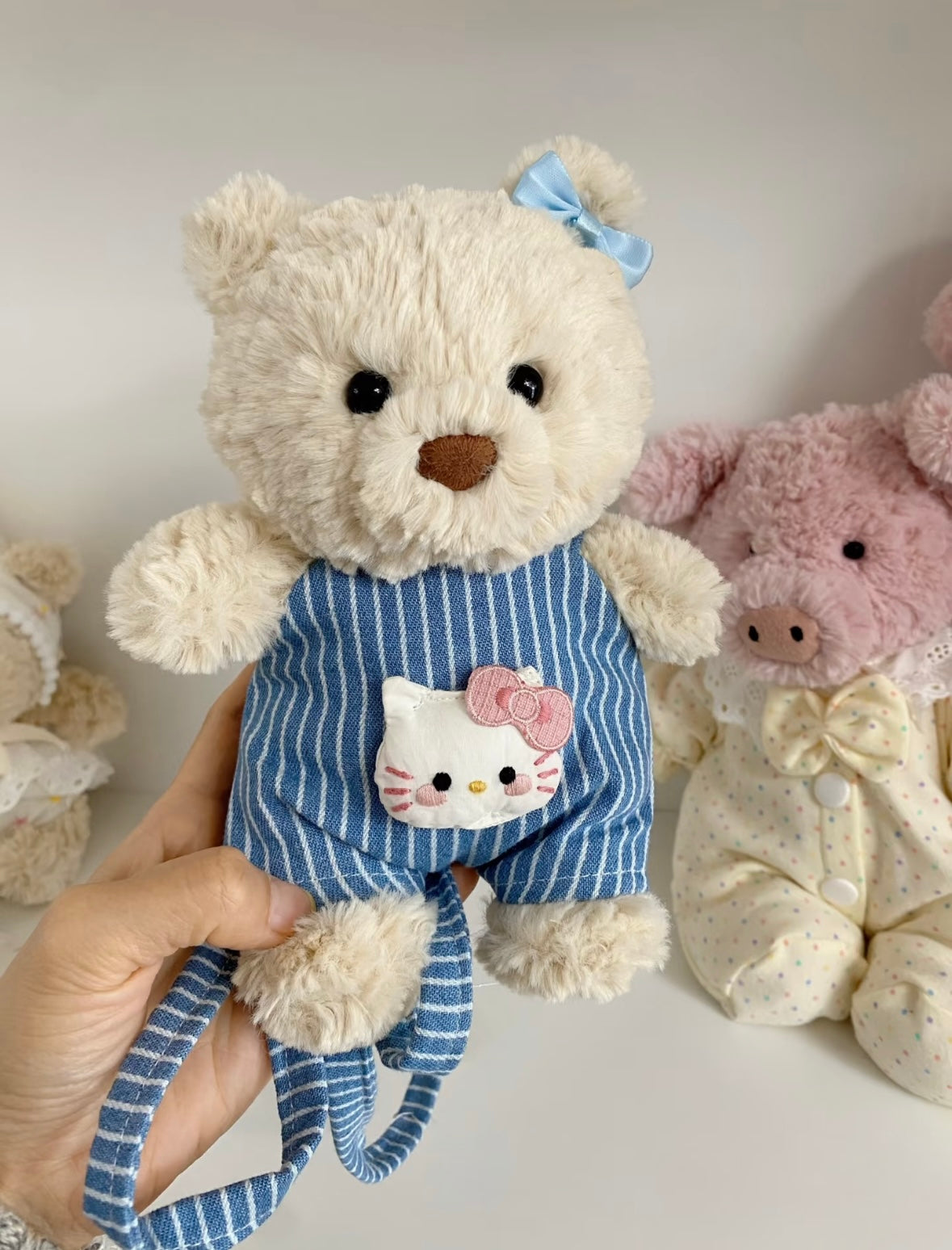 Close-up of blue striped dungaree with Hello Kitty embroidered patch, held in hand