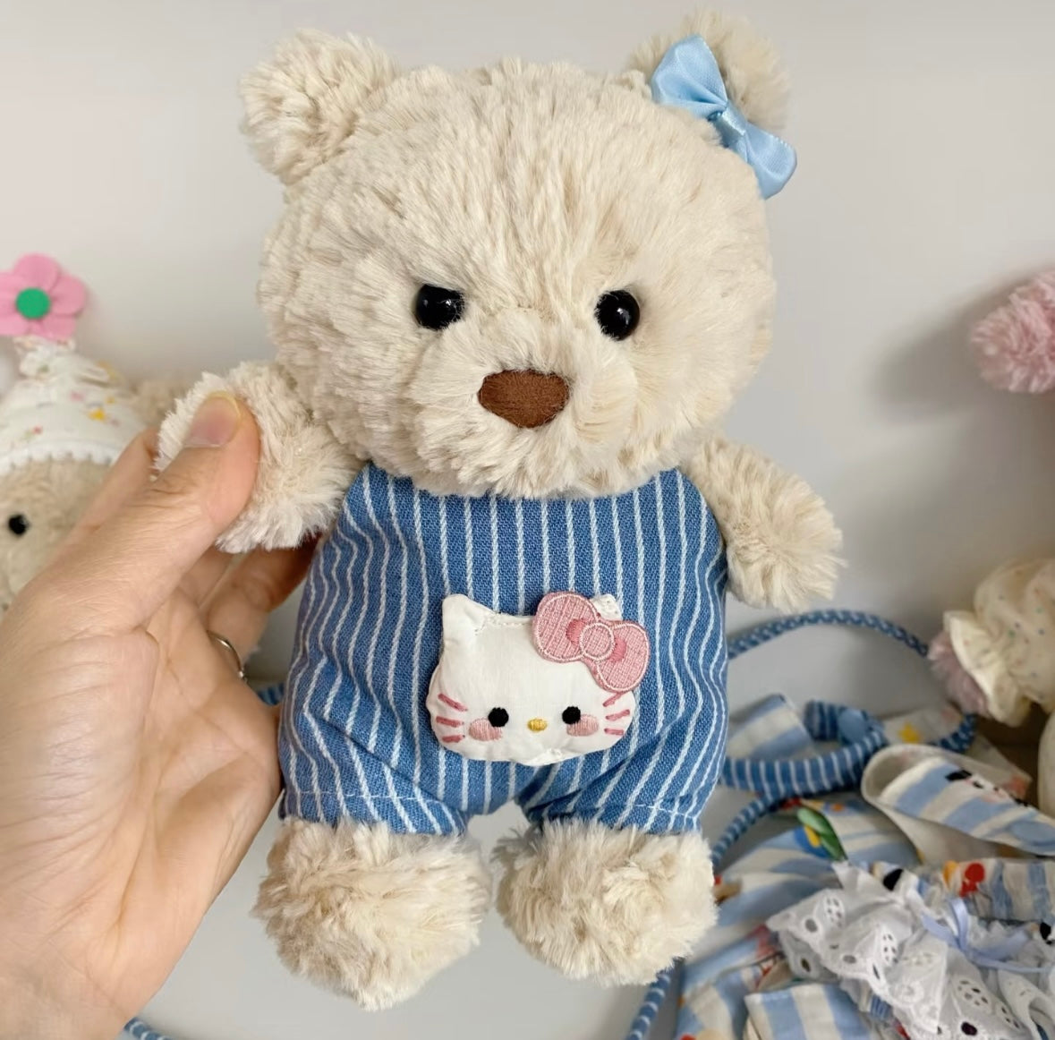 Back view of Jellycat bear in blue striped dungaree showing button fastenings and crossbody strap