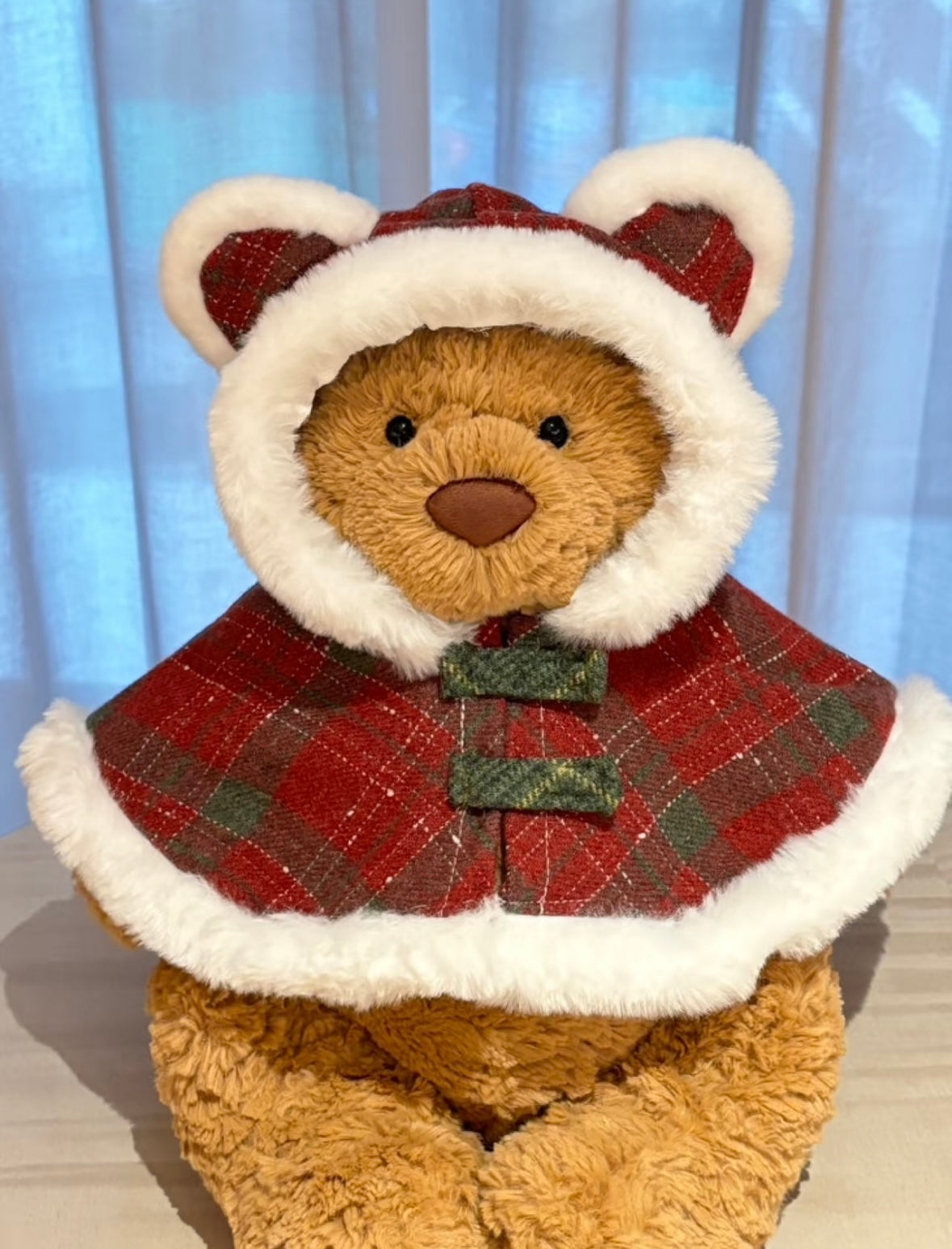 Bartholomew Bear wearing festive red tartan tweed cape with sherpa trim and bear ear hood