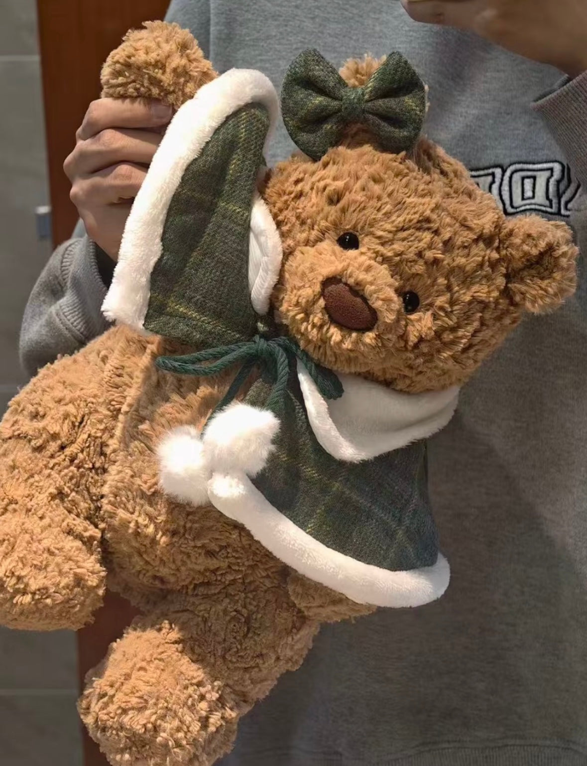 Bartholomew Bear wearing forest green tartan mini cape with green bow and Santa hat