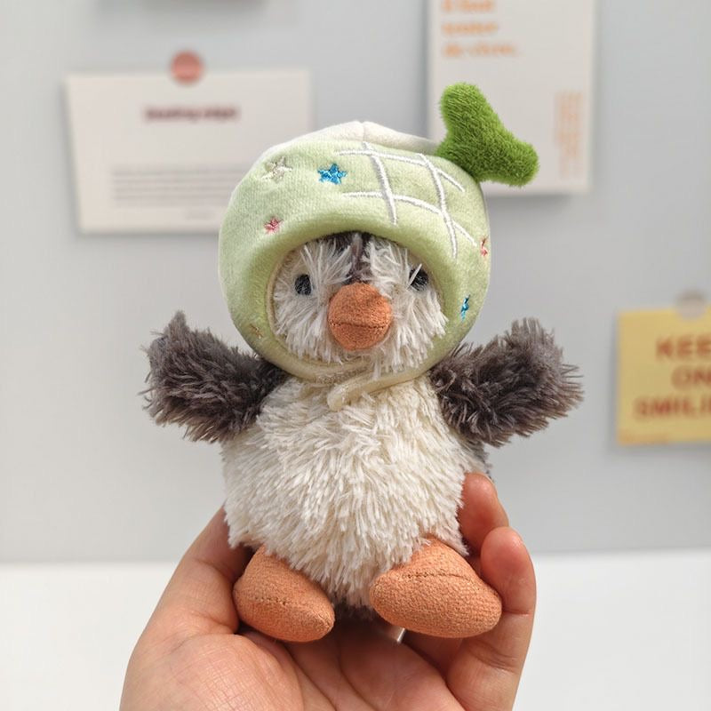 Jellycat Peanut Penguin wearing green avocado hat with plush stem
