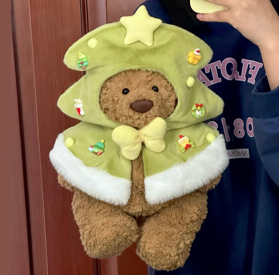 Bartholomew Bear wearing green Christmas tree cape with star and festive badges front view
