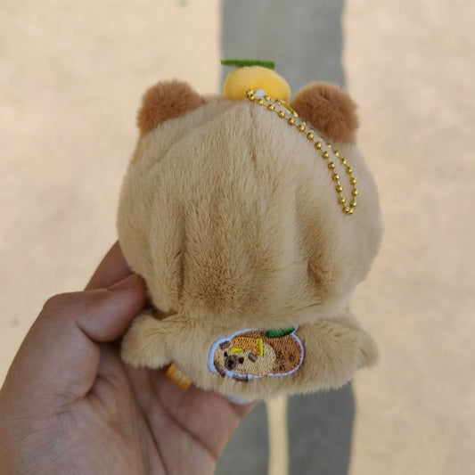 Capybara yuzu plush keychain back view showing embroidered badge and gold chain
