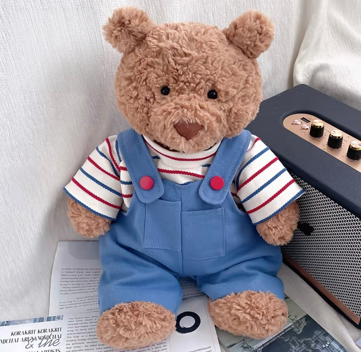 Bartholomew Bear wearing blue striped dungaree set, seated next to a vintage radio