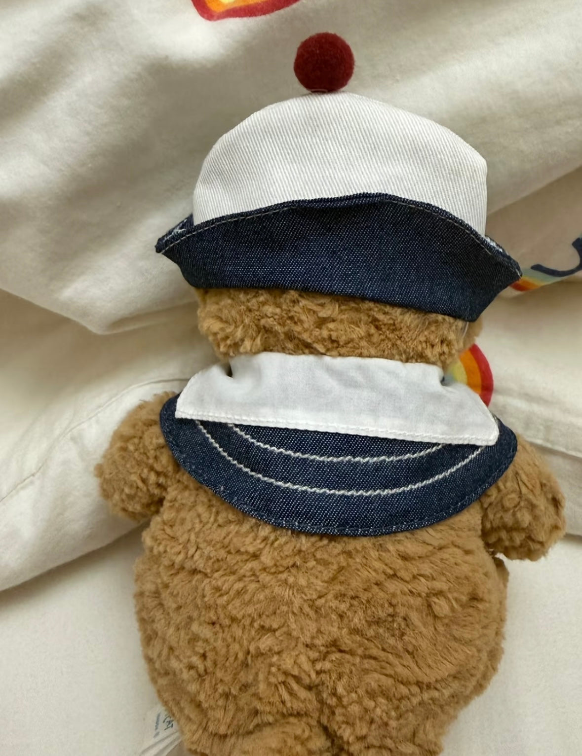 Back view of Bartholomew Bear wearing the denim sailor hat and collar set, showing white collar reverse and navy denim brim