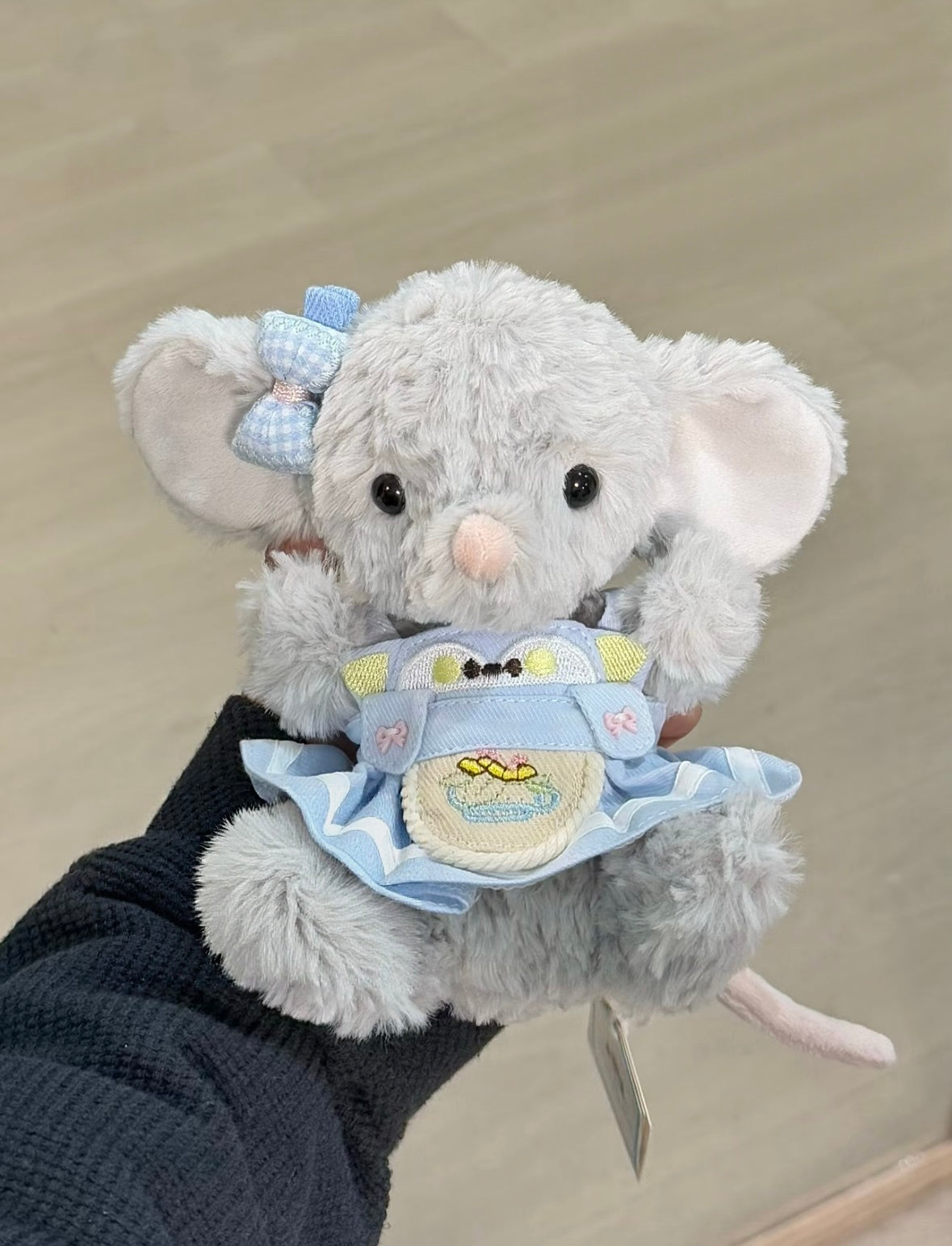 Grey elephant plush wearing a sky-blue frog bib outfit with gingham bow