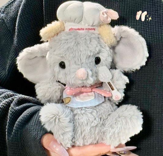 Grey elephant plush wearing a chef hat, pink bow tie and light blue bib outfit