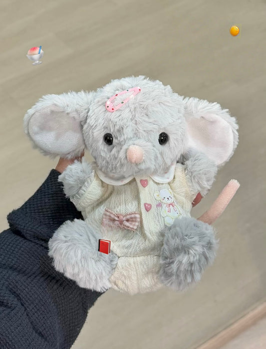 Grey elephant plush wearing a cream knit cardigan with bunny-print scarf, pink bow, hair clip and fluffy pom-pom tail