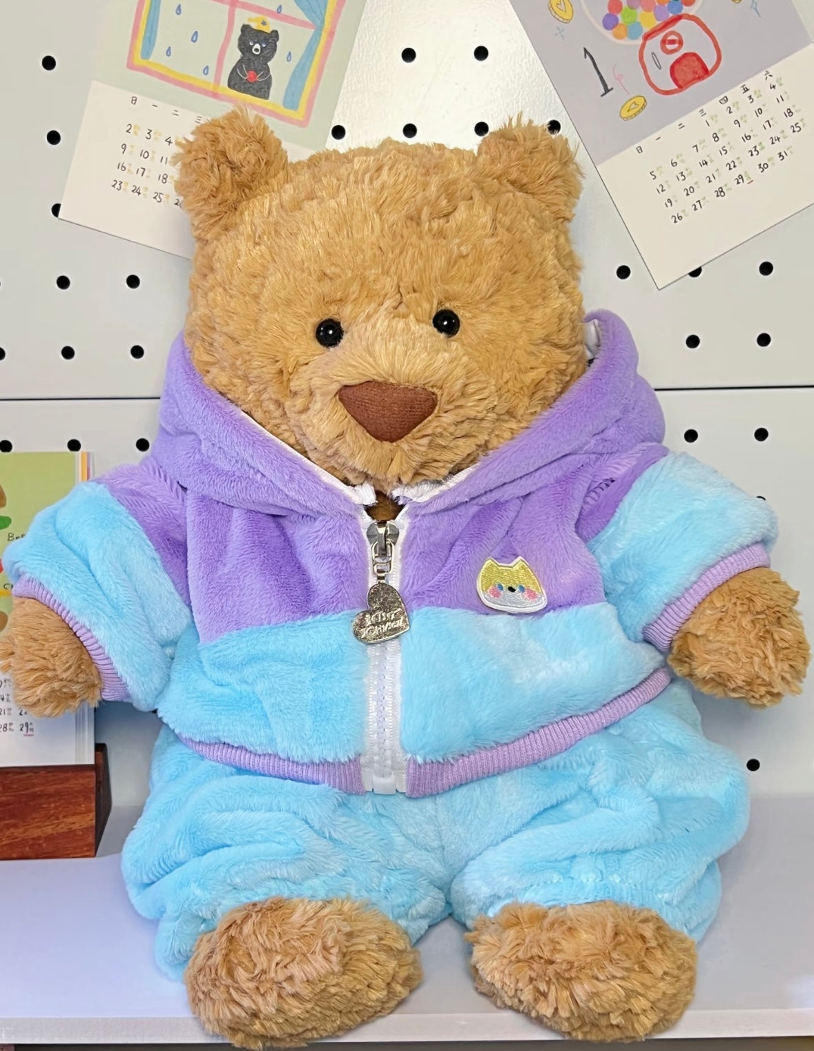 Brown teddy bear wearing pastel blue and lilac hoodie jumpsuit - front close up without hood