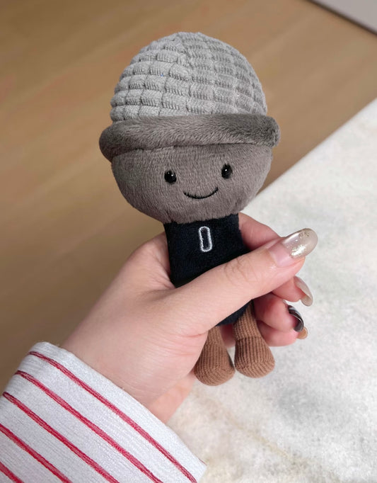 Plush microphone toy with smiley face and grey ribbed head held in hand - front view