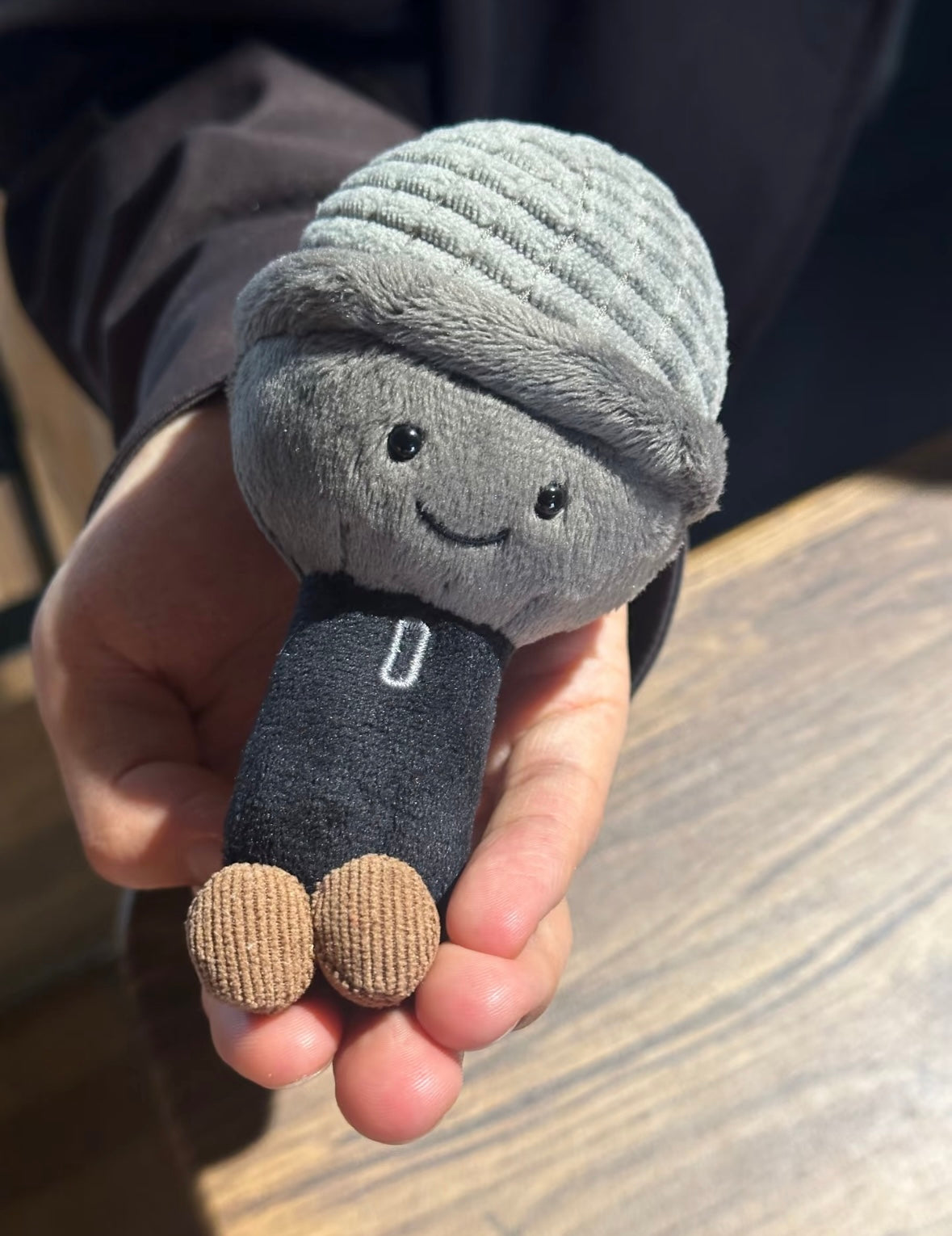 Plush microphone toy showing corduroy feet held in palm - front view