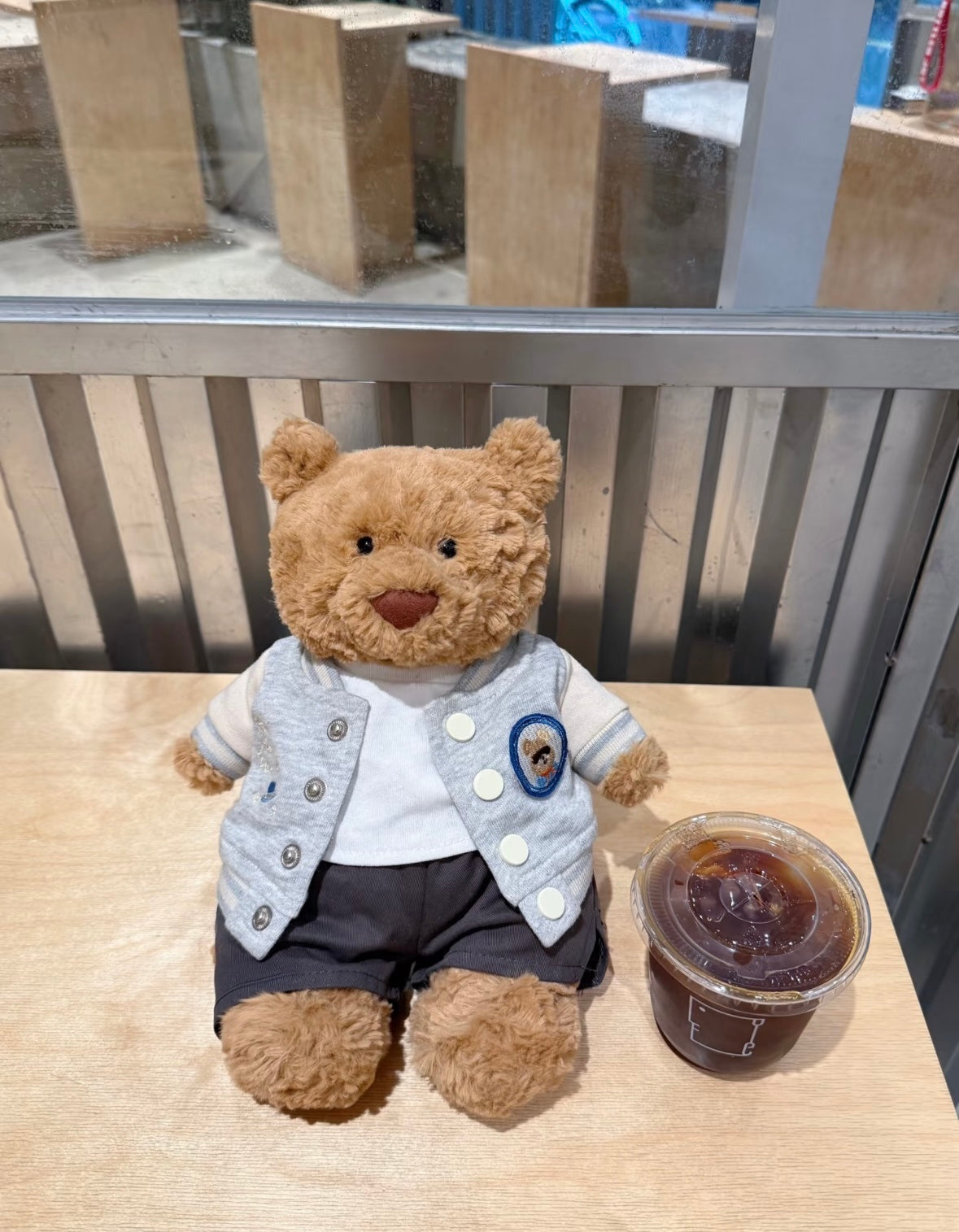 Bartholomew Bear wearing varsity set - seated café table view