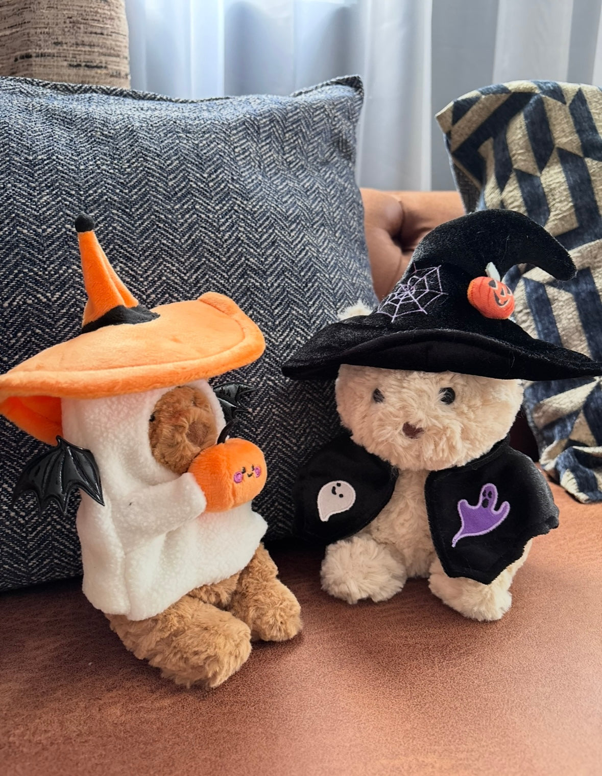 Back view of plush bear in black witch hat and cape showing spider web embroidery detail