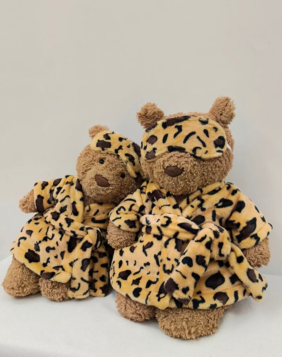 Large and small Bartholomew Bear both wearing leopard print robes and sleep masks - size comparison