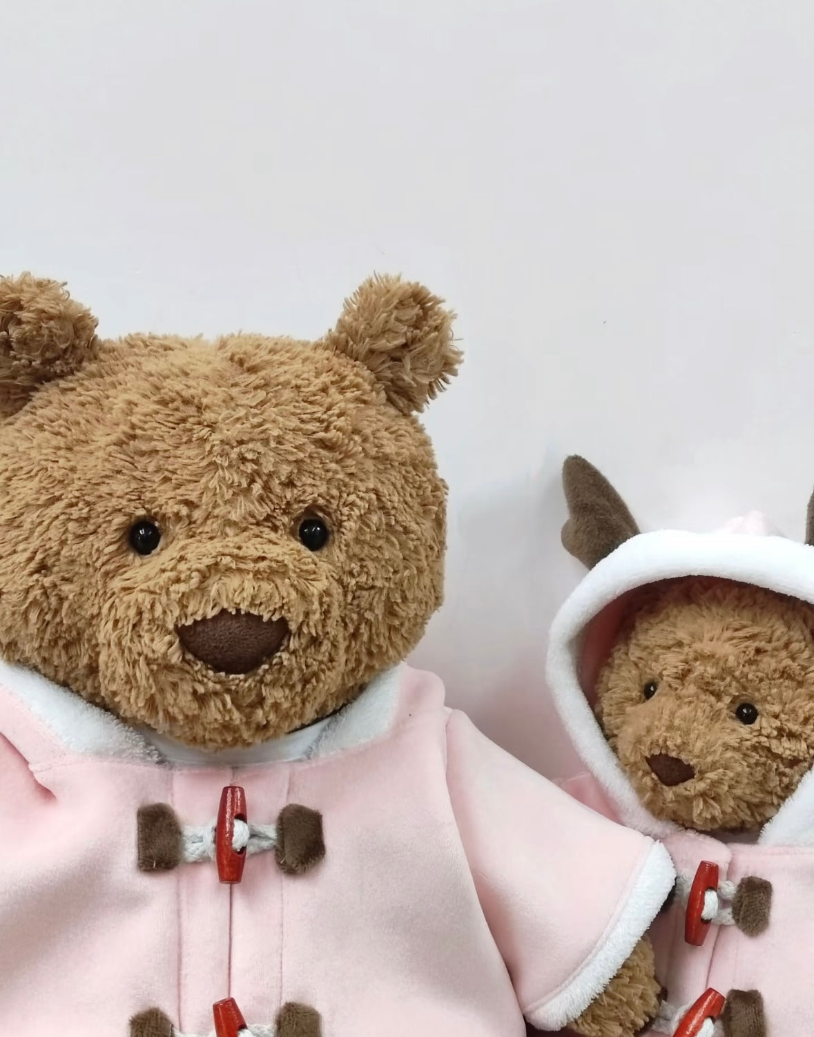 Close up of Bartholomew Bear and Reindeer faces wearing pink duffle coats showing toggle detail