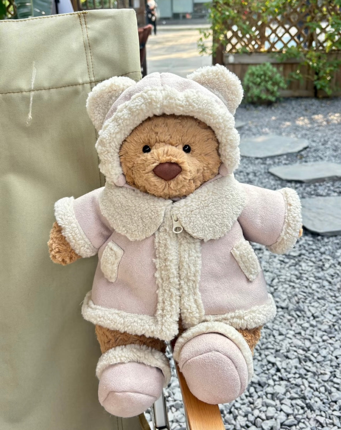 Bear and pig plush in cream shearling outfits on bench
