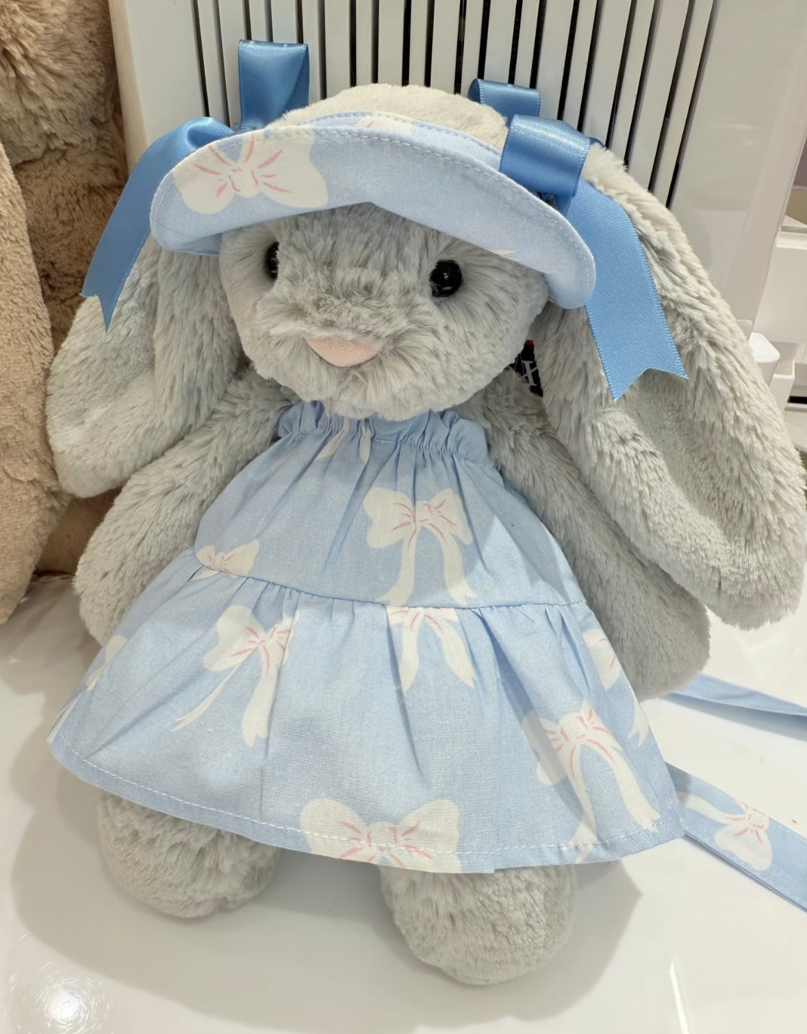 Bashful Bunny wearing baby blue bow-print tiered dress with matching sun hat, front view