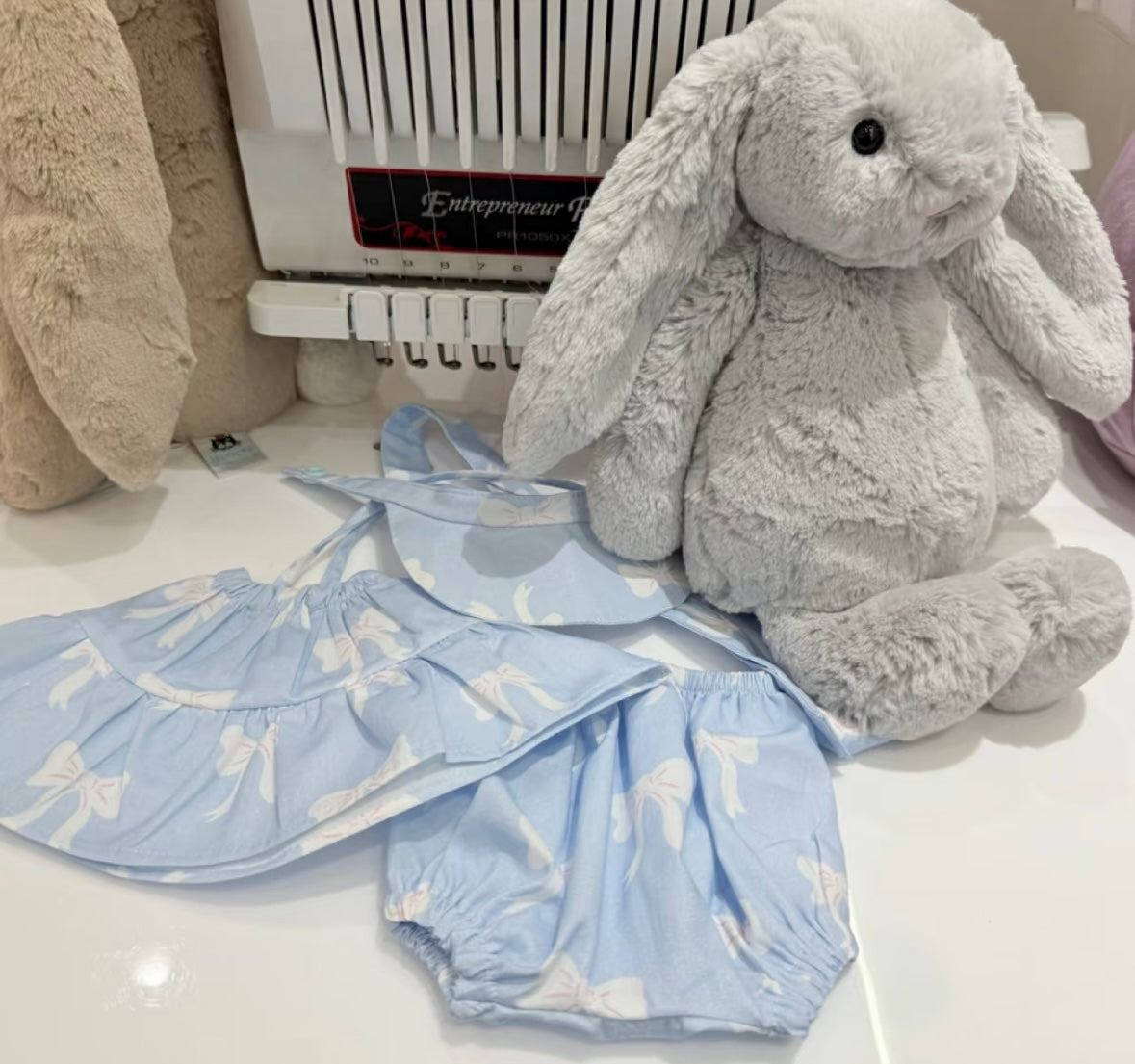 Blue bow dress set laid flat beside Bashful Bunny