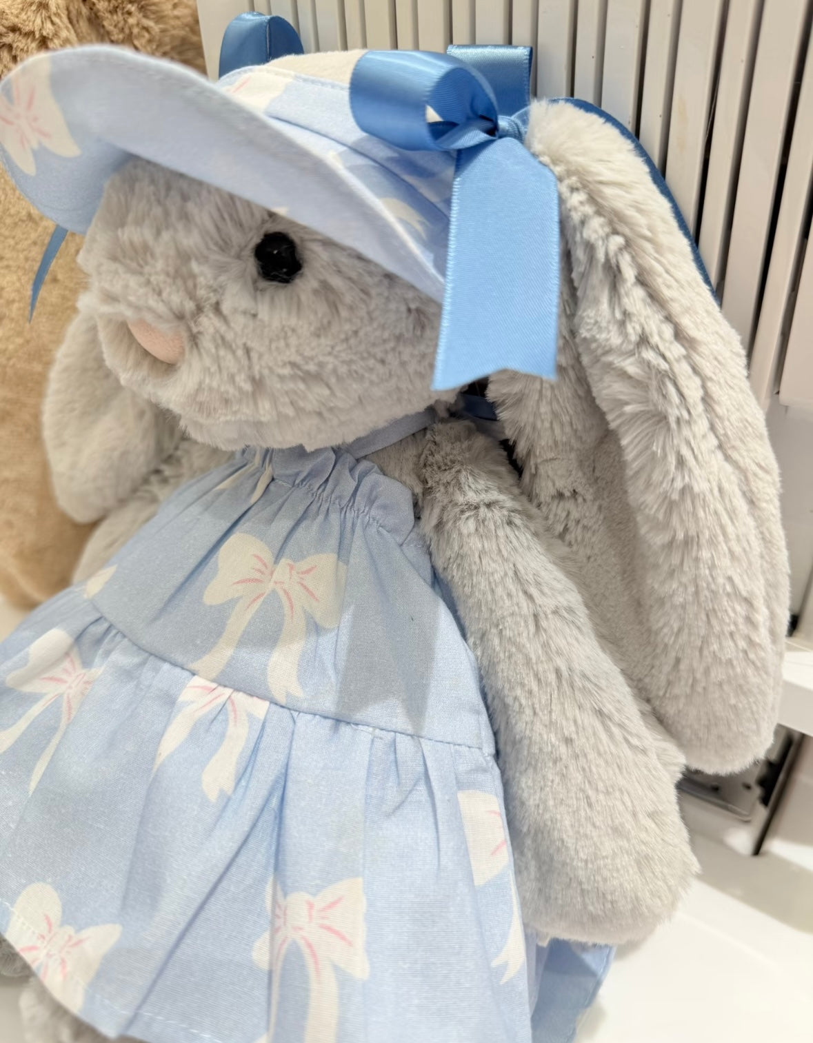 Close-up of Bashful Bunny in blue bow dress with satin ribbon sun hat