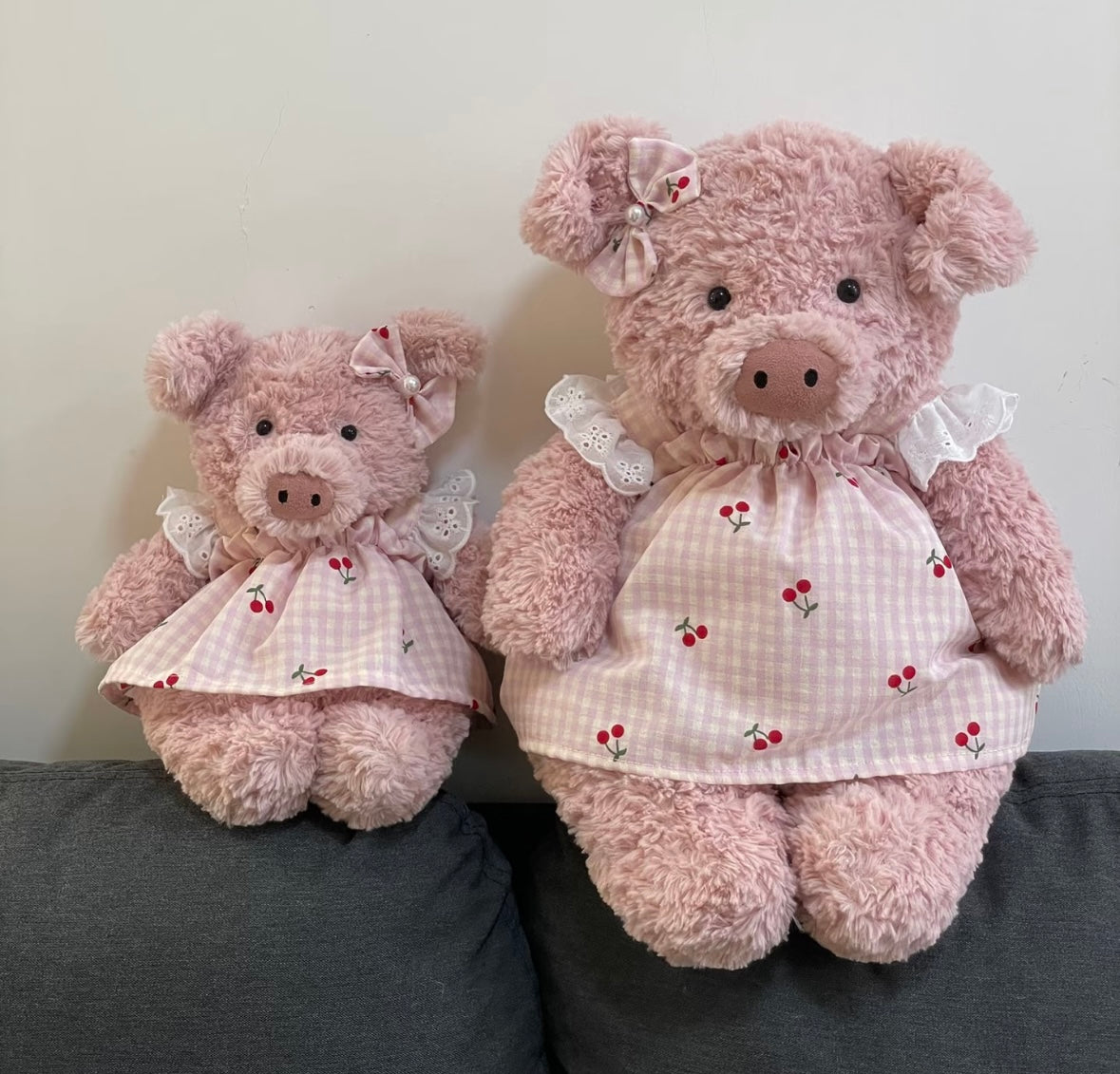 Pink and blue cherry gingham dress sets worn by two pink pig plush toys in different sizes