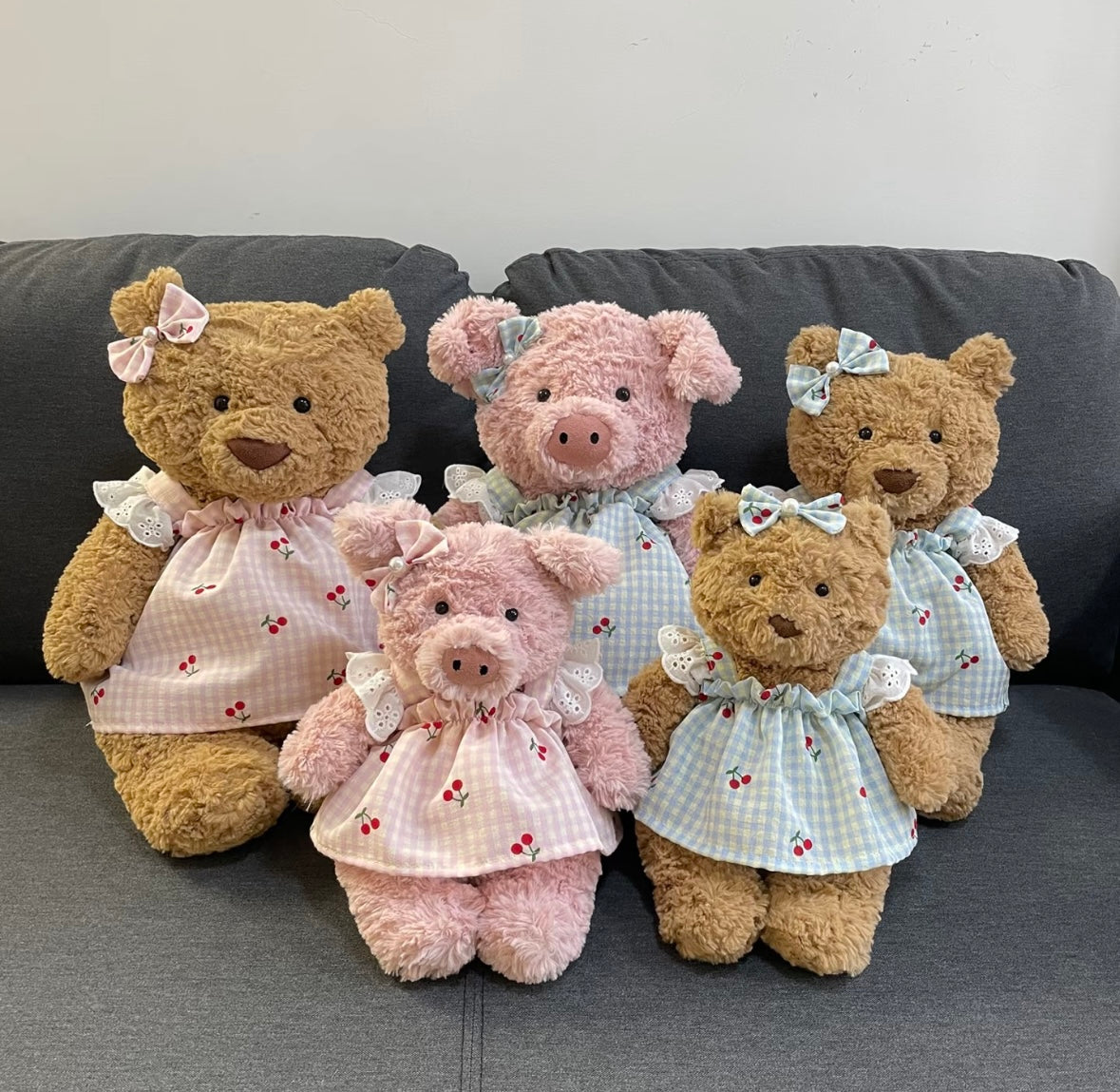 Group photo of cherry gingham dress sets in pink and blue on pink pigs and brown bears