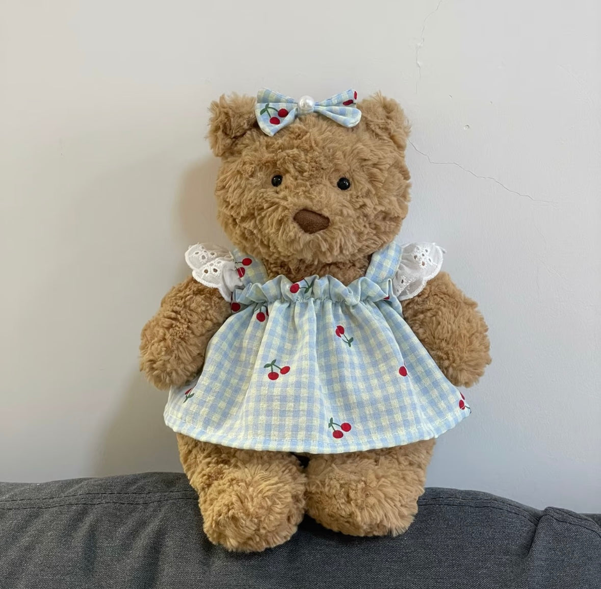 Brown bear plush wearing blue cherry gingham dress with broderie anglaise collar and bow hair clip