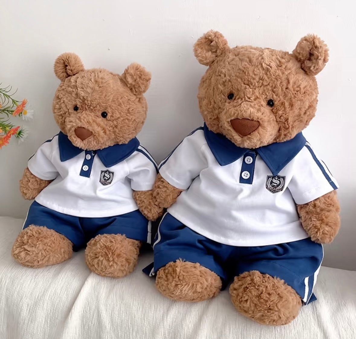 Two brown bear plush toys wearing navy polo sport sets — small and large sizes side by side