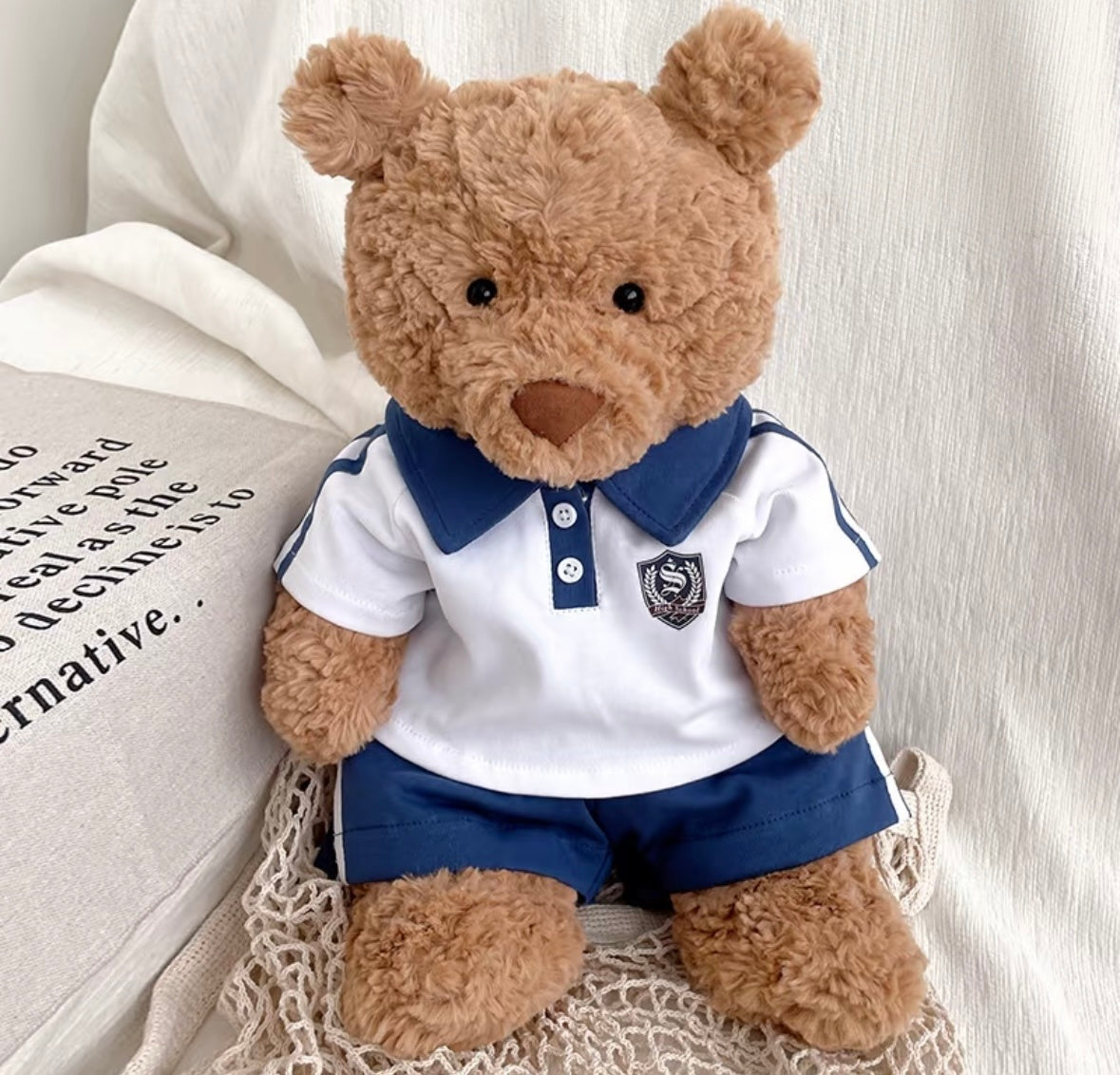 Large brown bear plush wearing white and navy polo shirt with navy sport shorts, front view