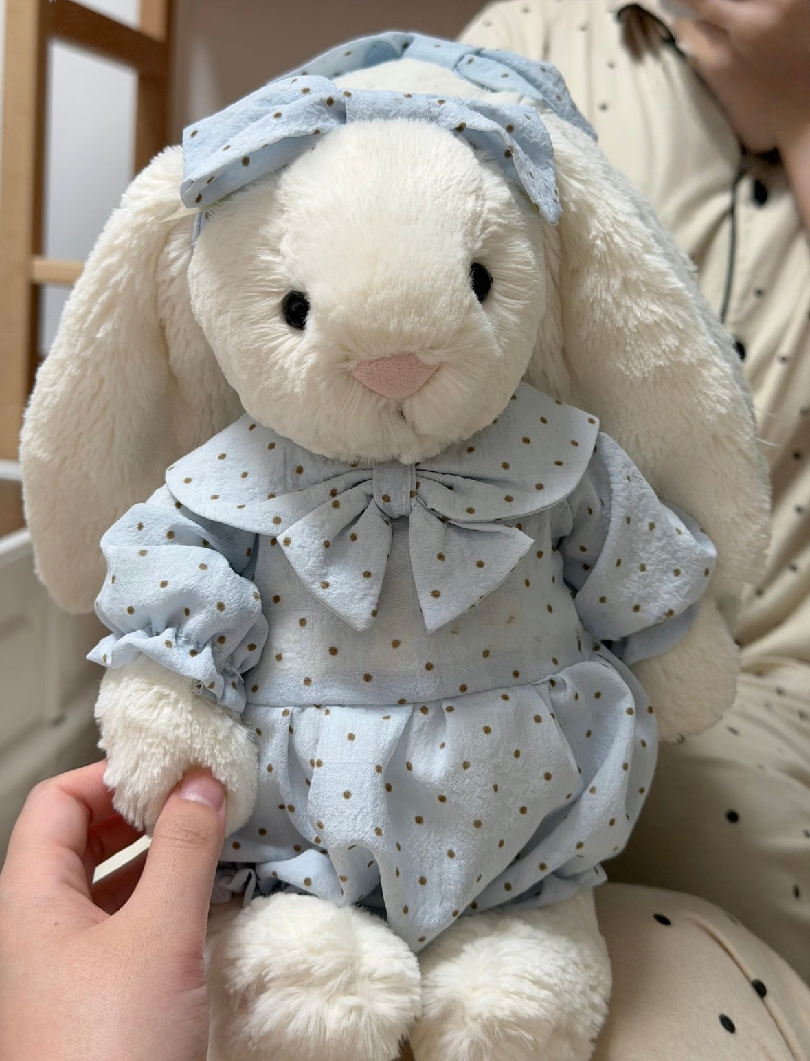 Cream polka dot romper set on white bunny plush - held view
